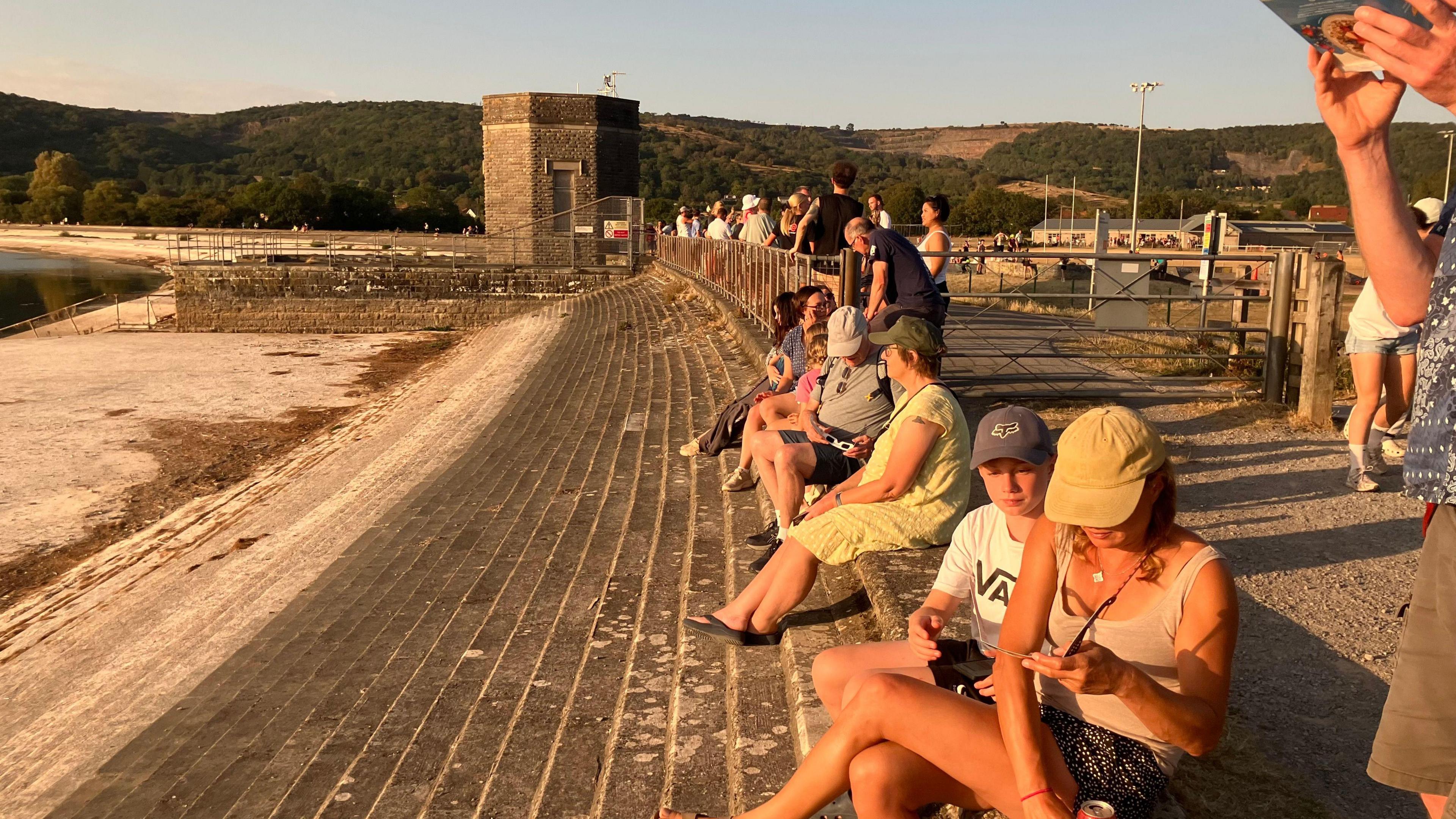 People are sat on stone steps looking at the sun