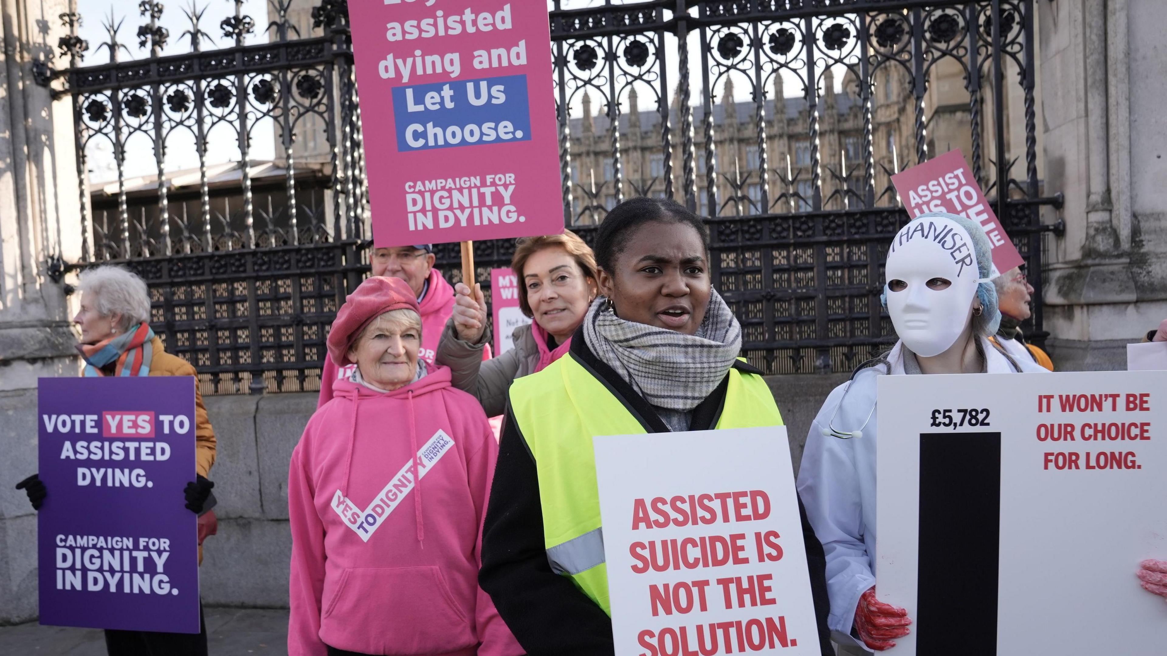 People in support of and opposing the Terminally Ill Adults (End of Life) Bill demonstrate outside the Houses of Parliament in Westminster, London. Supporters wearing pink hoodies with purple signs saying 'Vote yes to assisted dying. Campaign for dignity in dying".
Opposers are wearing white masks with signs saying 'assisted suicide is not the solution".