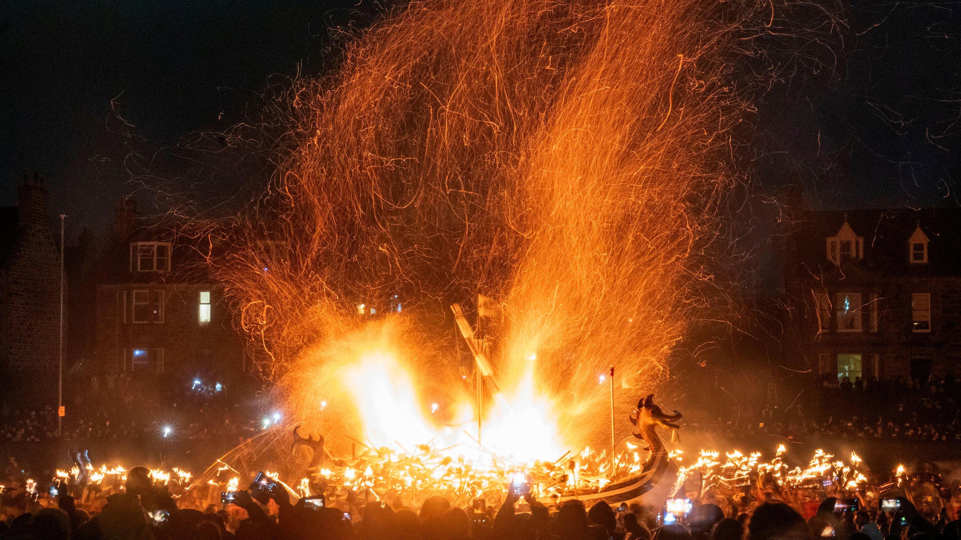 viking longboat on fire as lots of people watch on