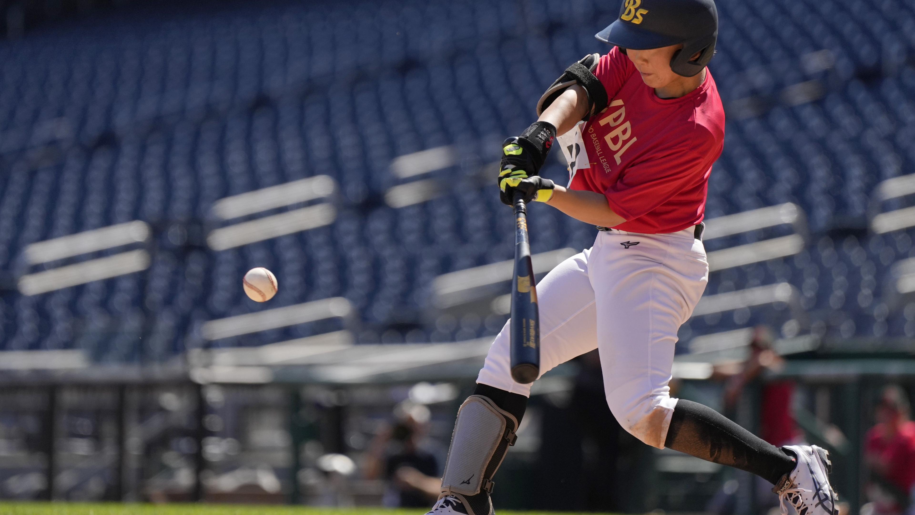 Woman baseball player smashes the ball with a dark blue bat