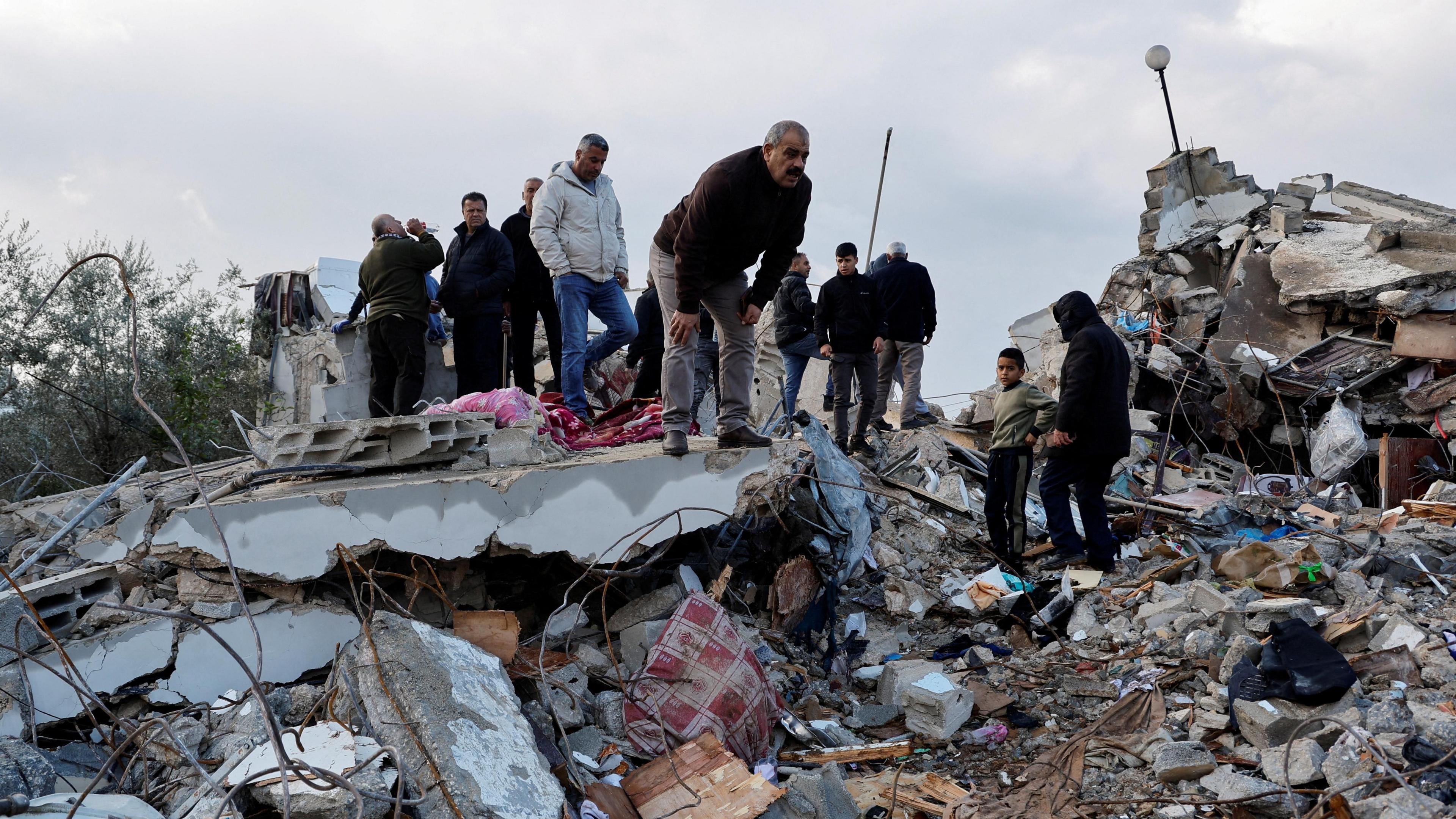 Palestinian inspect a building in Burqin, destroyed during an operation in which Israeli security forces killed two Palestinian men accused of killing three Israelis in an attack in the occupied West Bank (23 January 2025)