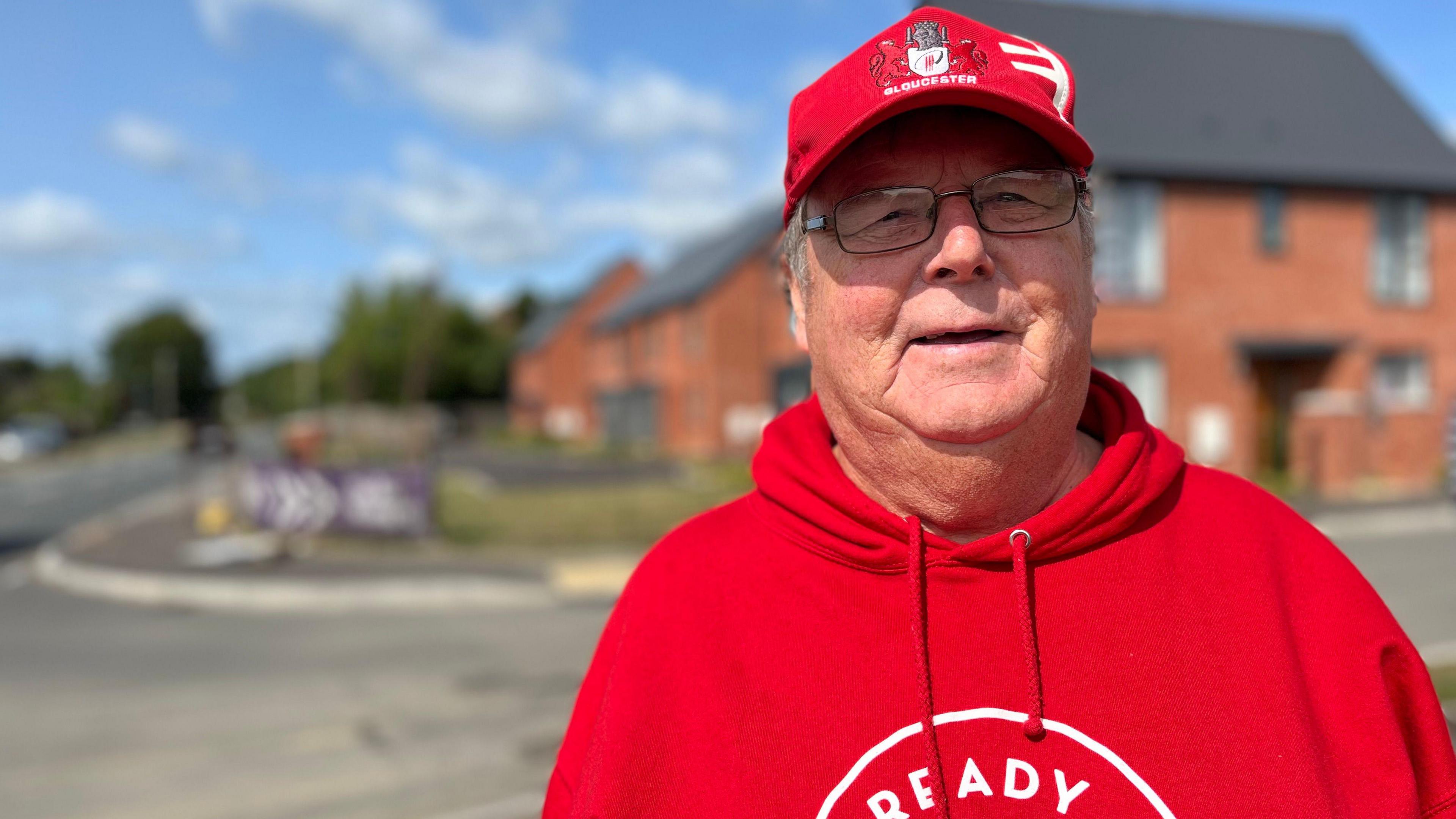 Innsworth resident stood in front of Whittle Gardens estate with a red jumper and red hat on. 