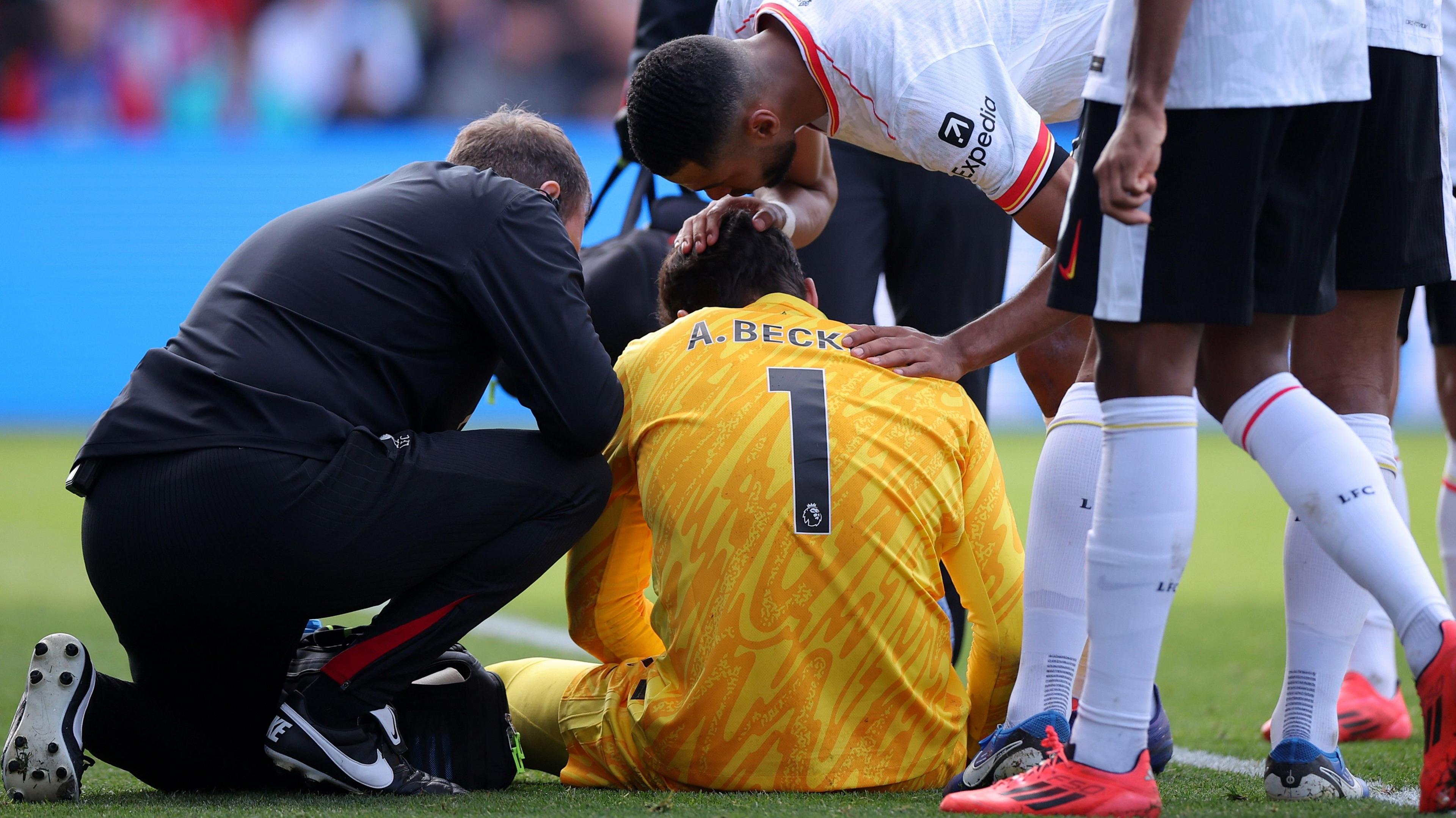 Alisson receives treatment on an injury from a member of Liverpool's medical staff