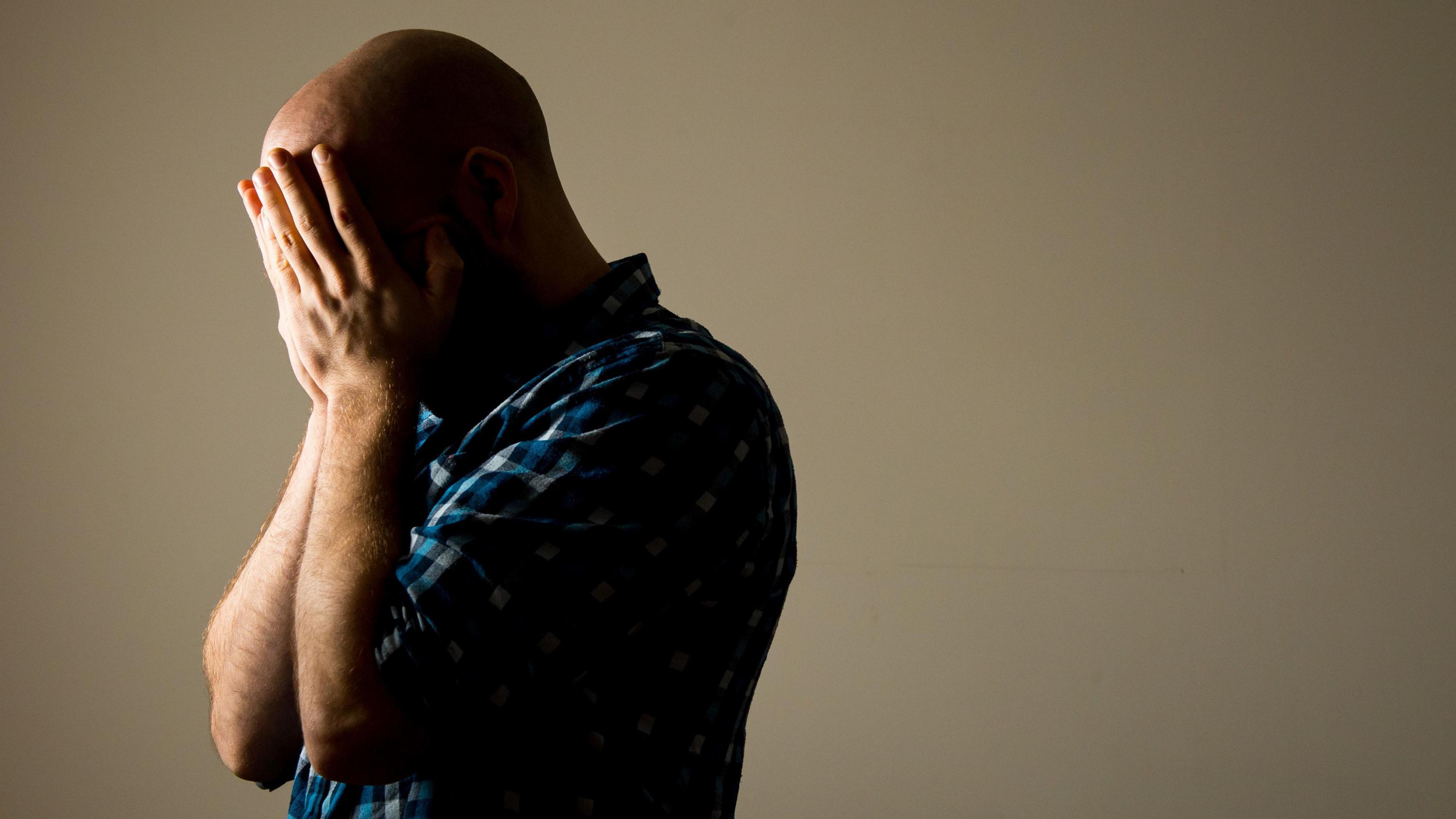 Man with his hands on his face in sadness 