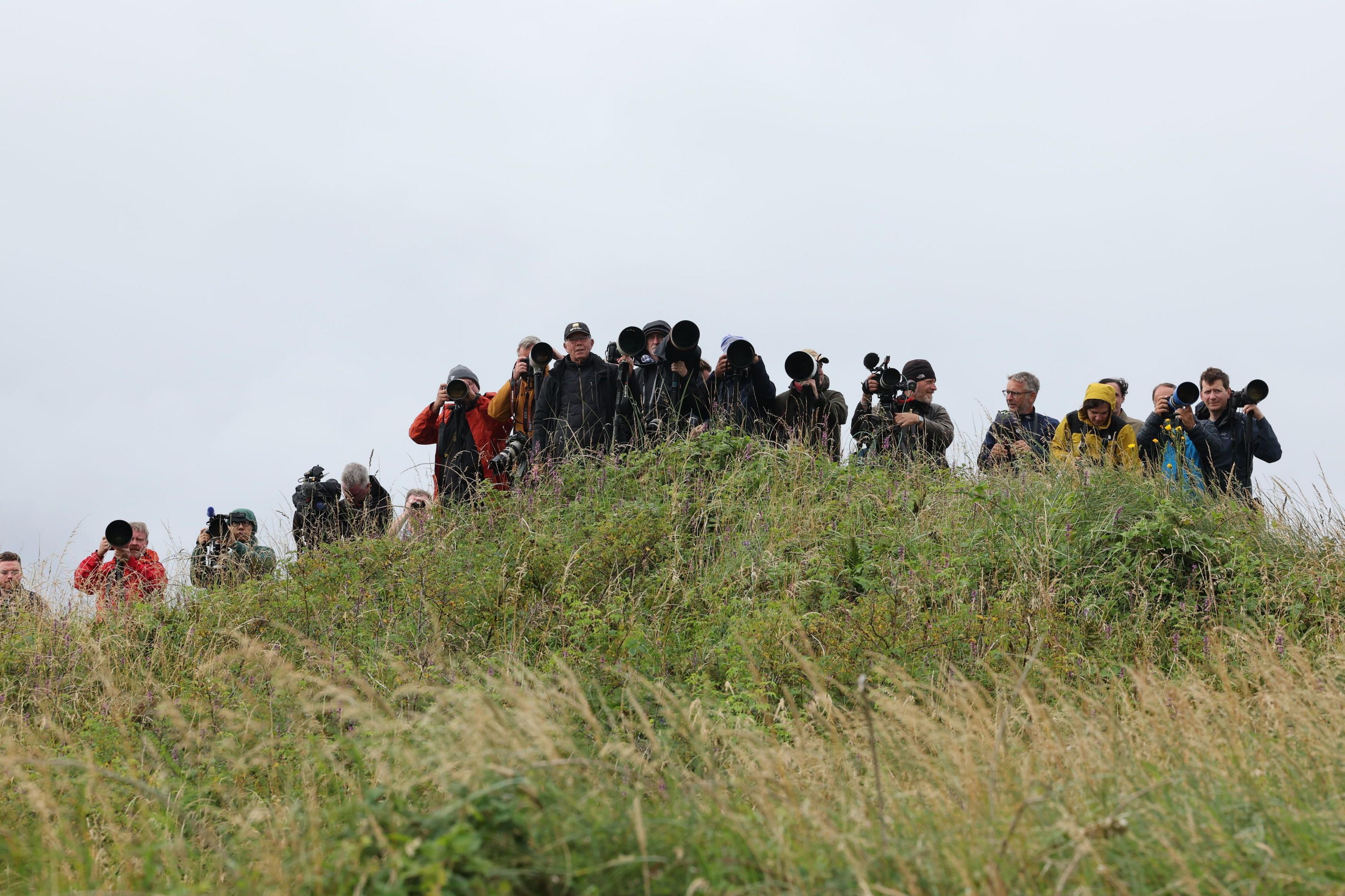 Journalists and photographers on a grassy hill at Turnberry