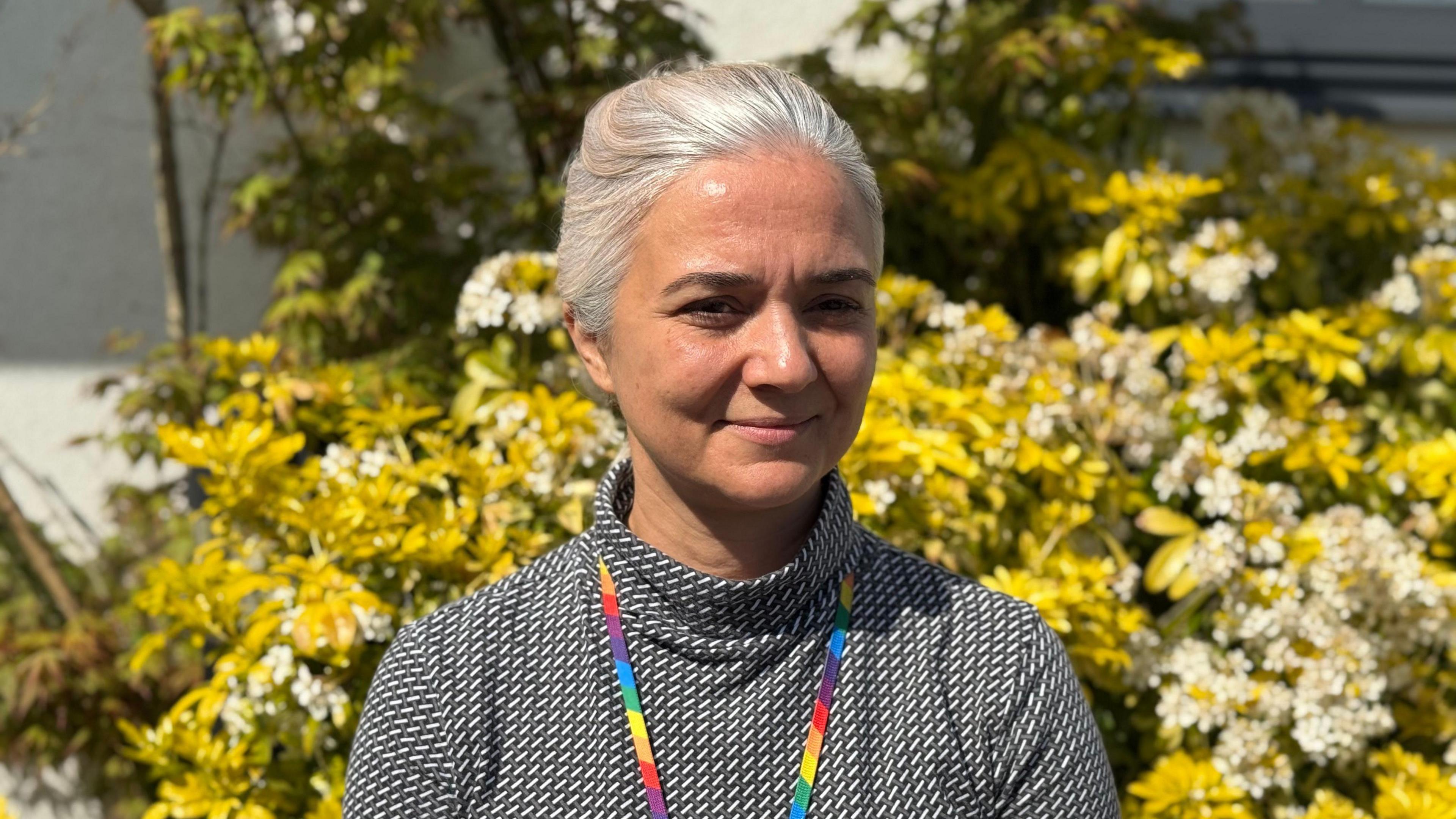 Zory Darman. She is wearing a black and white turtleneck top and has long grey tied back hair.