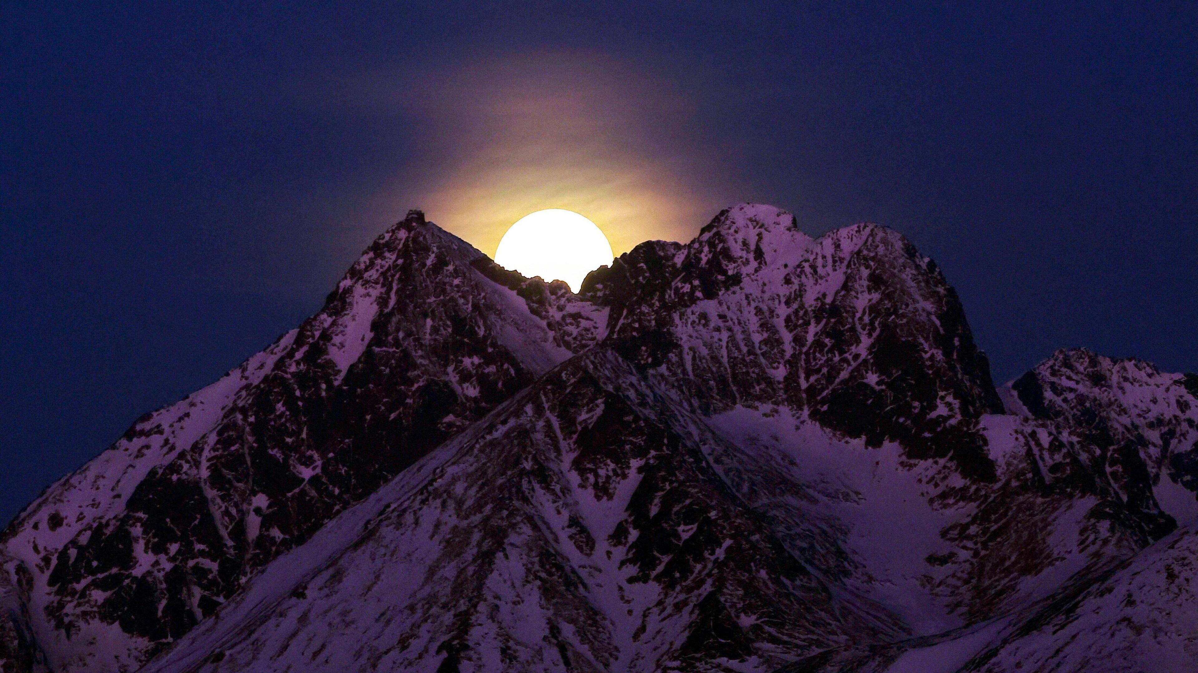 A moon on snowy mountain peaks