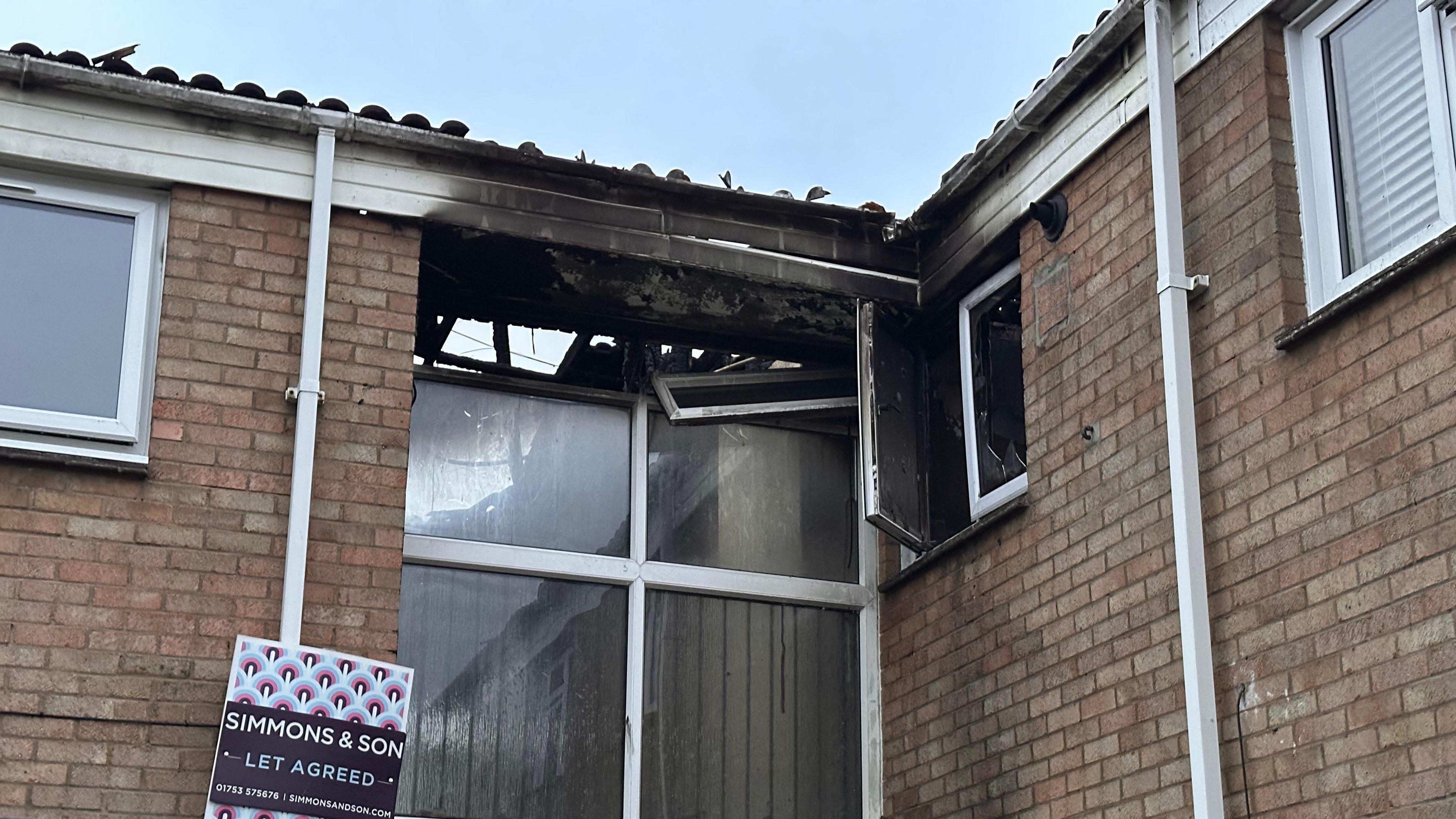 Damage from the fire visible to the roof and windows after the fire in the corner of the building.