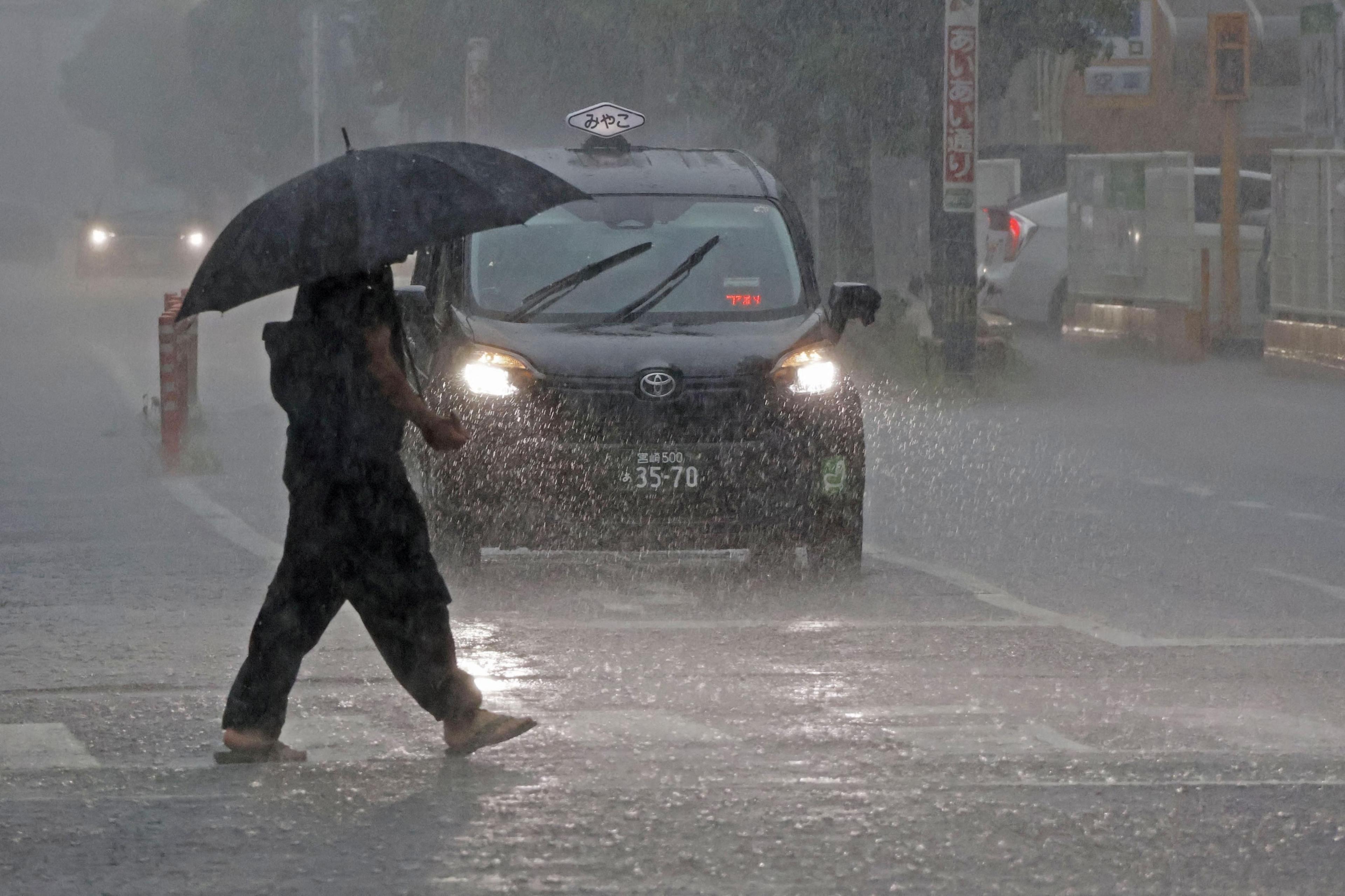 A person walks across a zebra crossing holding an umbrella in the rain