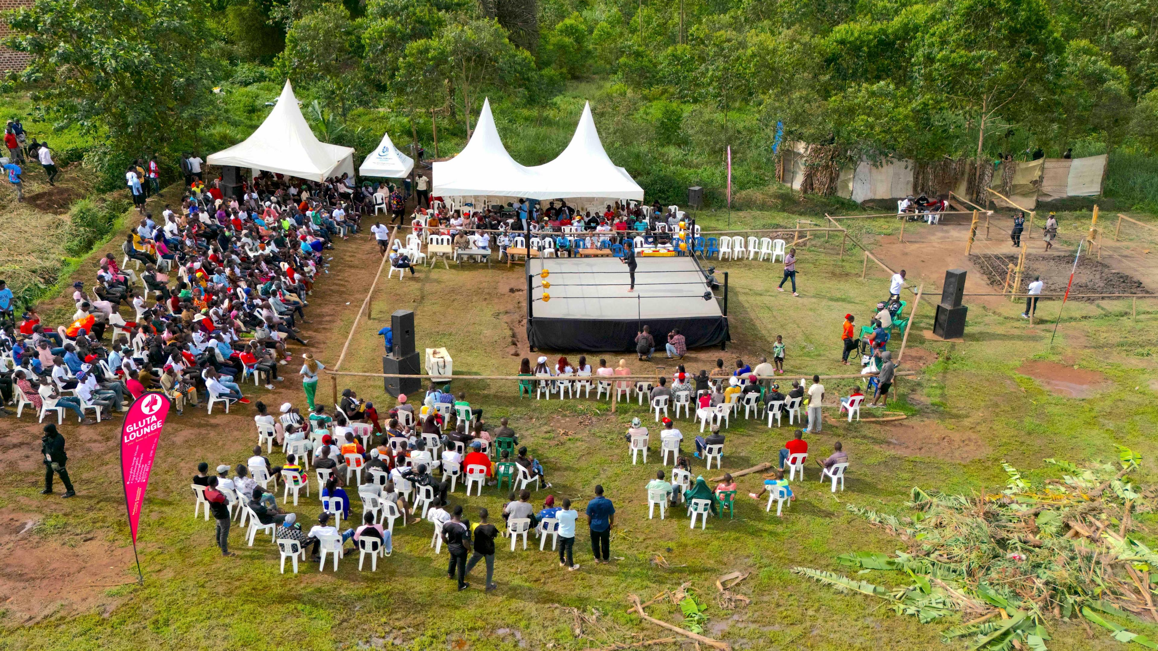 An aerial view of fans seated around a wrestling ring in a field in Uganda