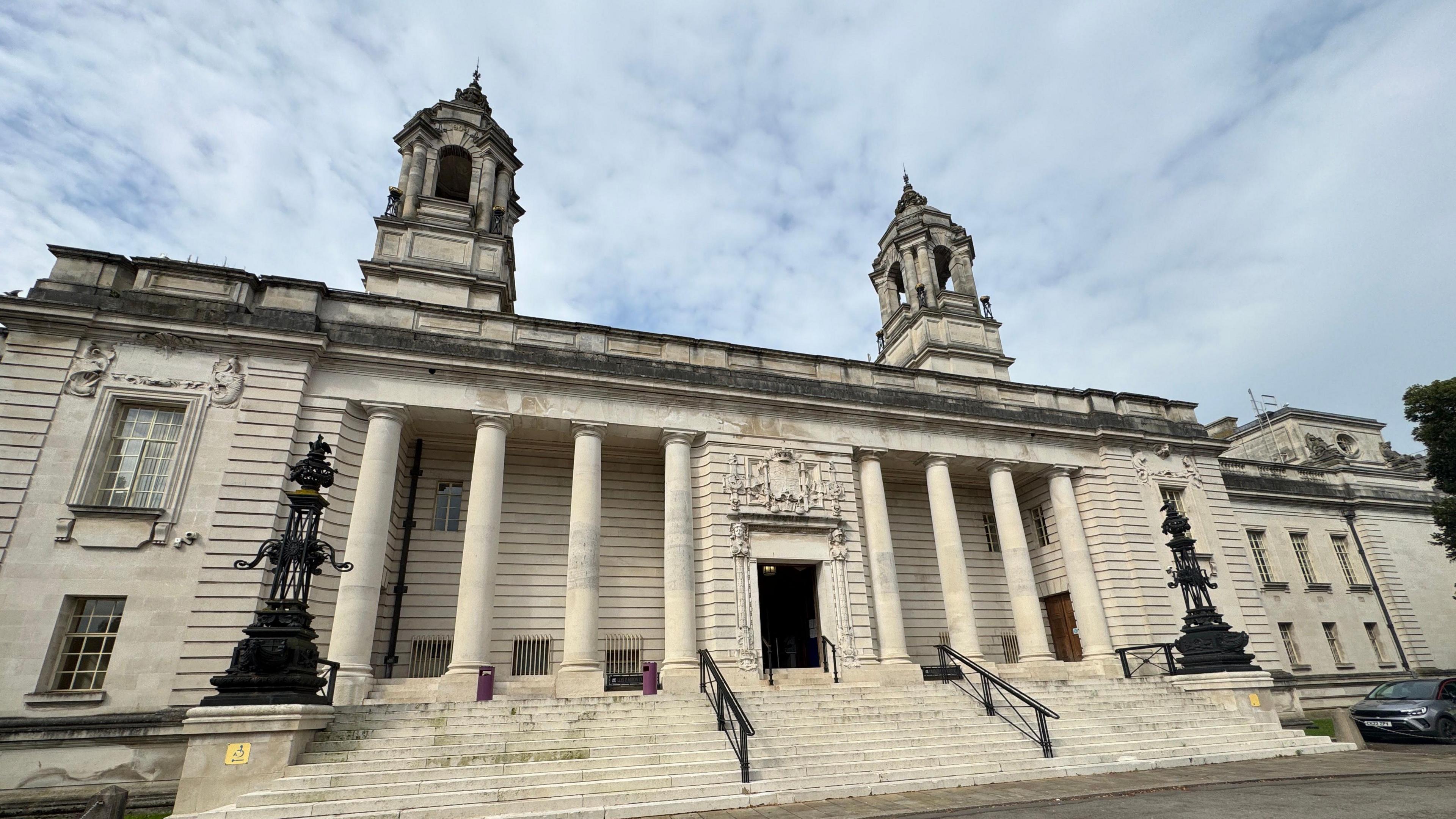 Outside of Cardiff Crown Court. There are steps leading up to the doors, which have four pillars on either side. 