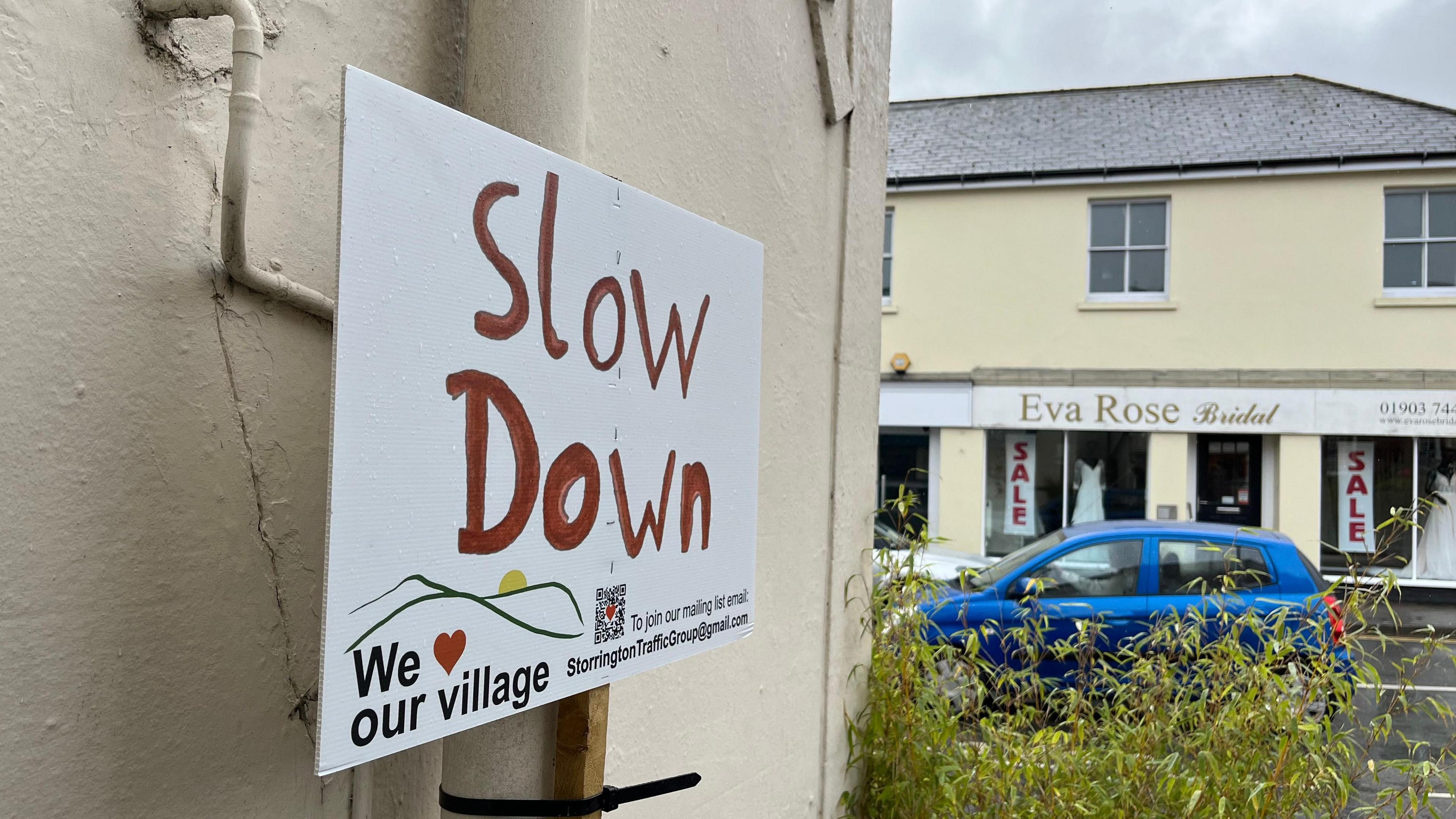 A sign which reads "slow down" in Storrington high street