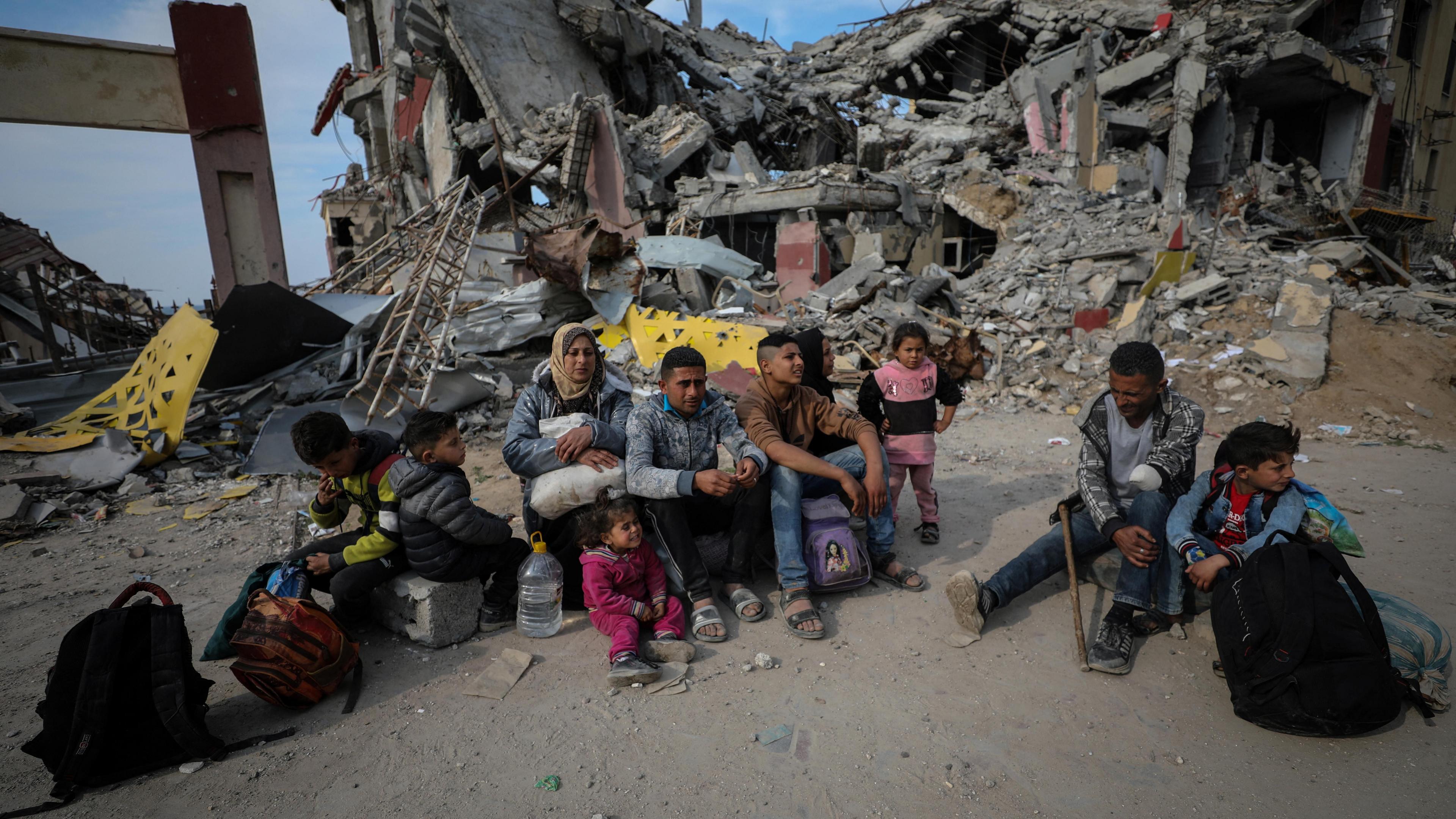 Displaced Palestinians from the Mohammed family sit on the rubble of destroyed buildings in the Gaza Strip (28 January 2025)