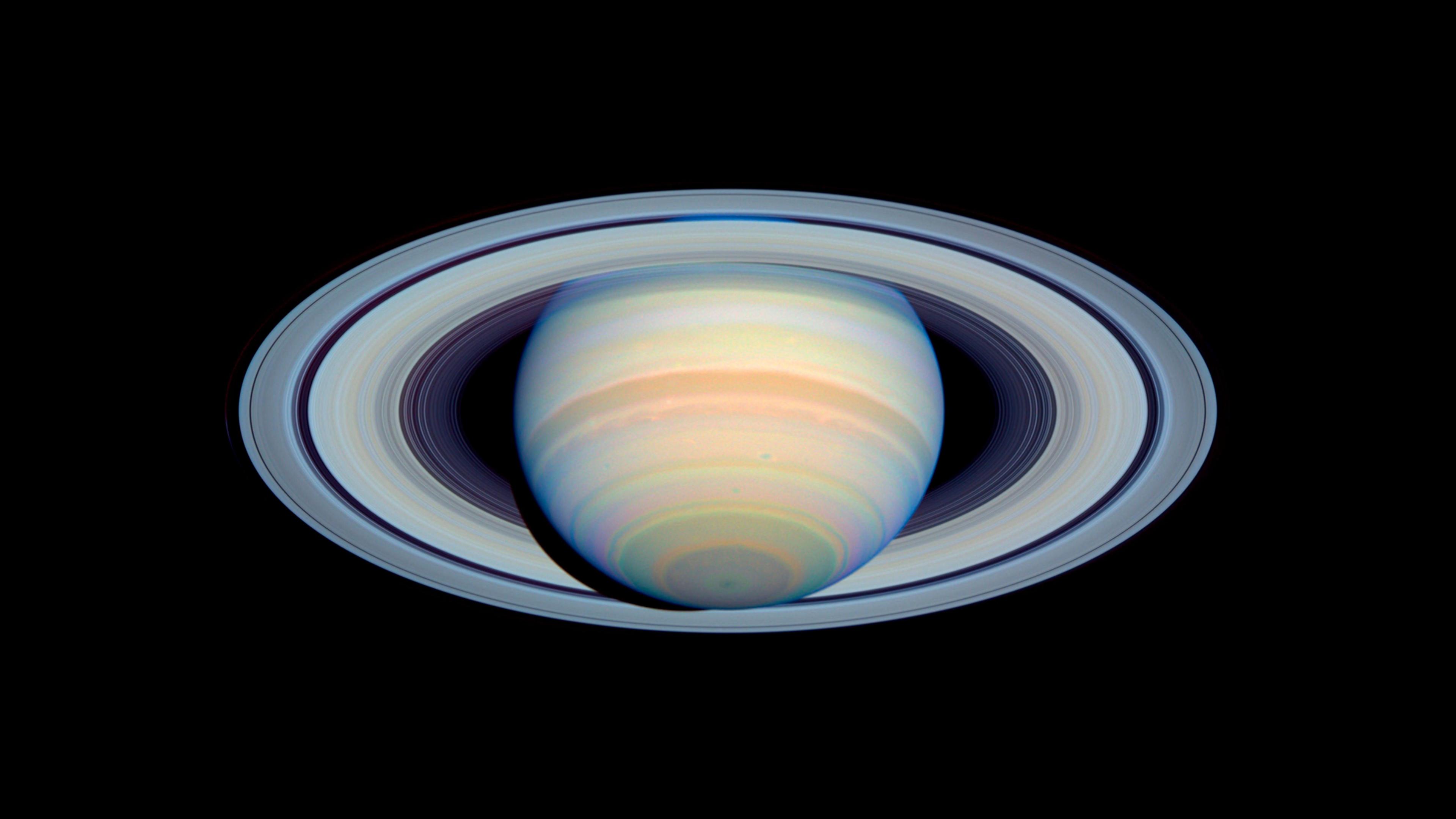  A round planet surrounded by rings against a dark background