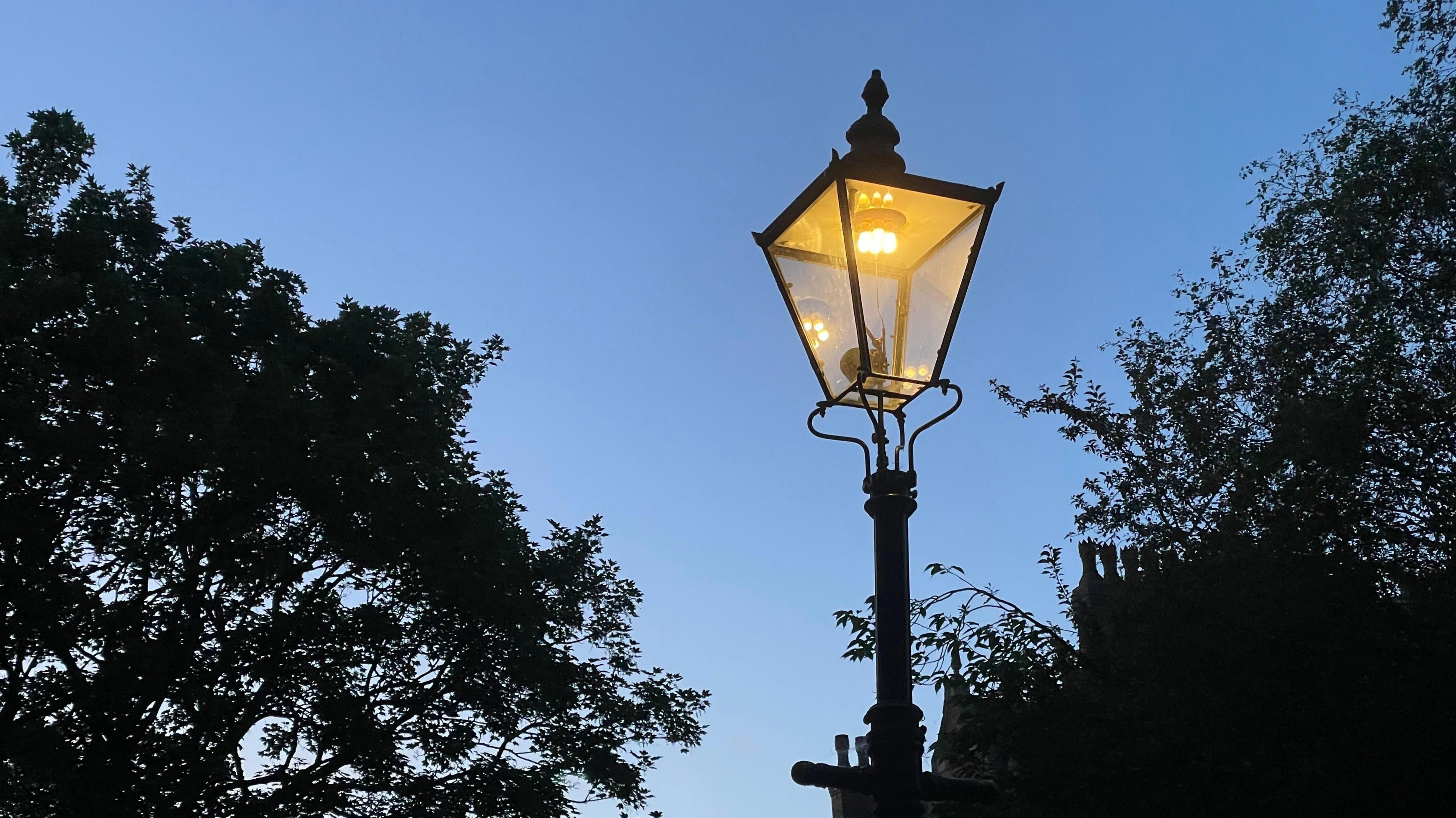 A gas lamp lit up at night in The Park, Nottingham
