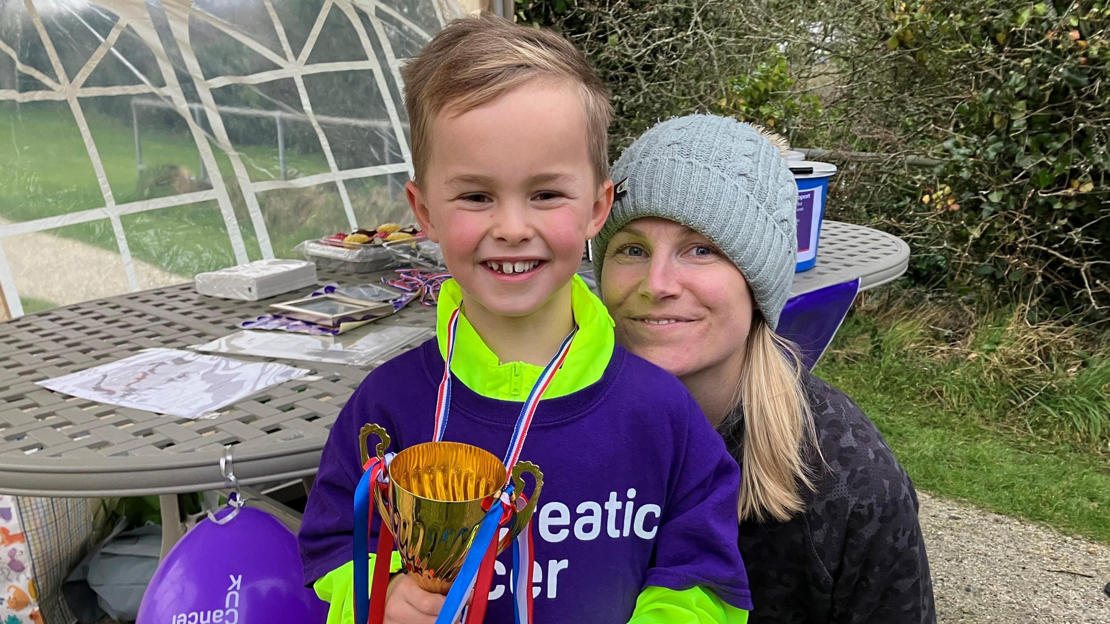 Oliver holding the trophy with his mum