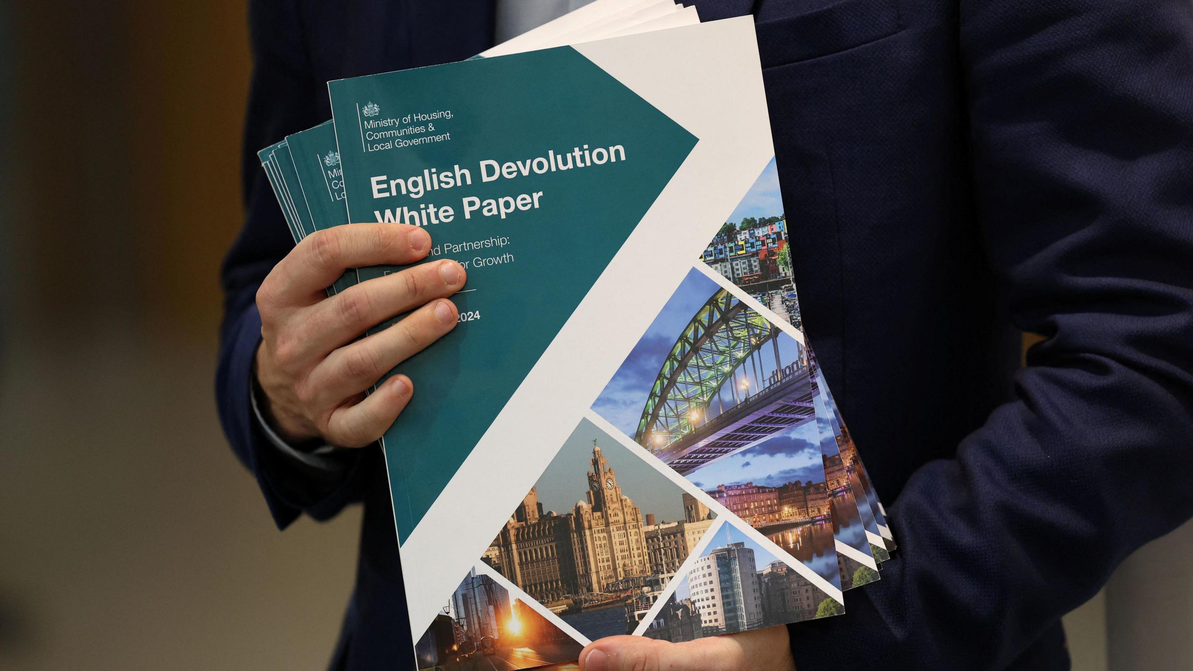 A man holds a Government document with the title "English Devolution White Paper"