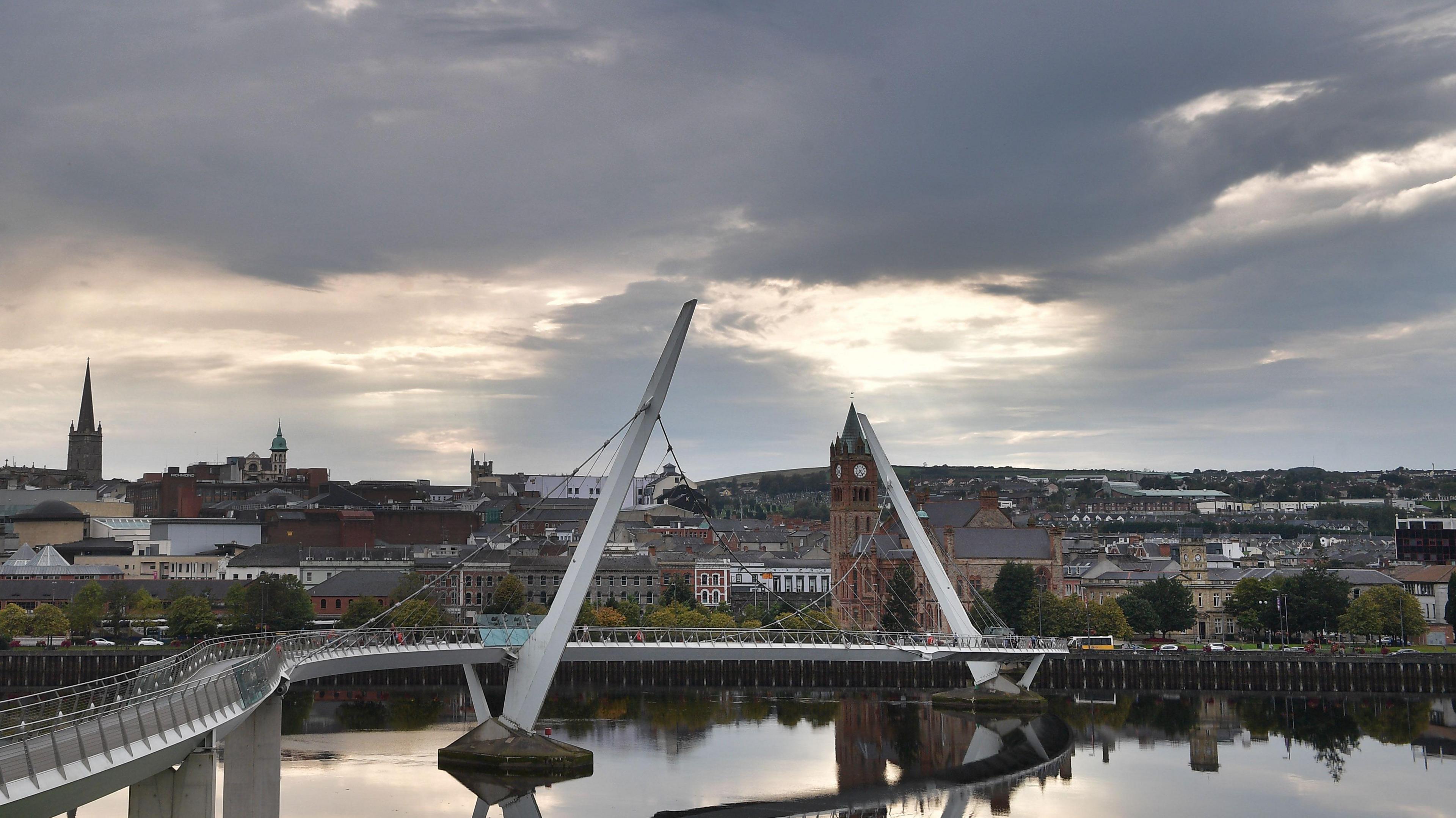Shows Derry's peace bridge with the Guildhall in the background and other buildings, including St Columb's cathedral and the former department store at Austin's