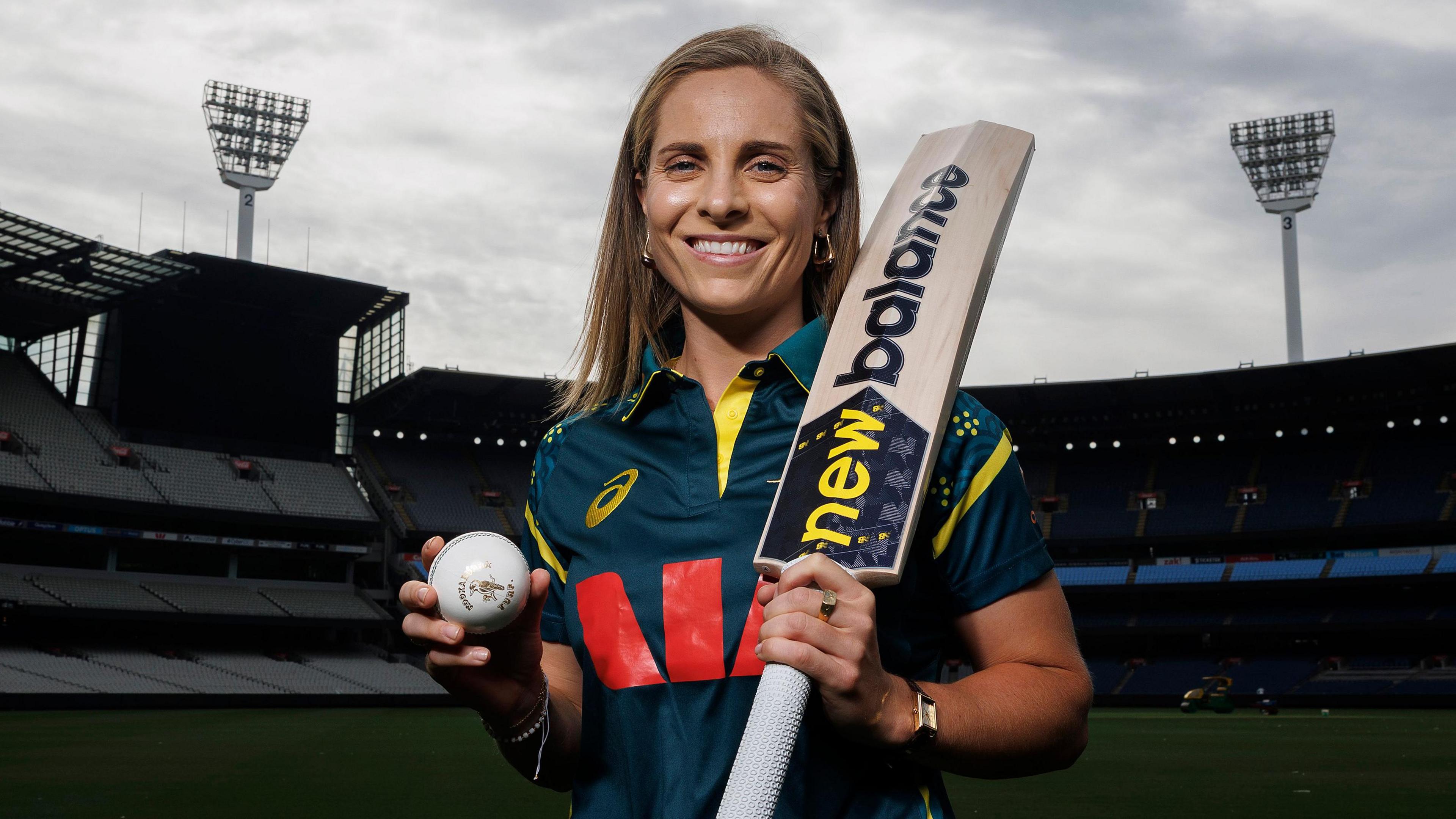 Australia all-rounder Sophie Molineux smiles as she holds up a bat and ball at a photoshoot after being named captain
