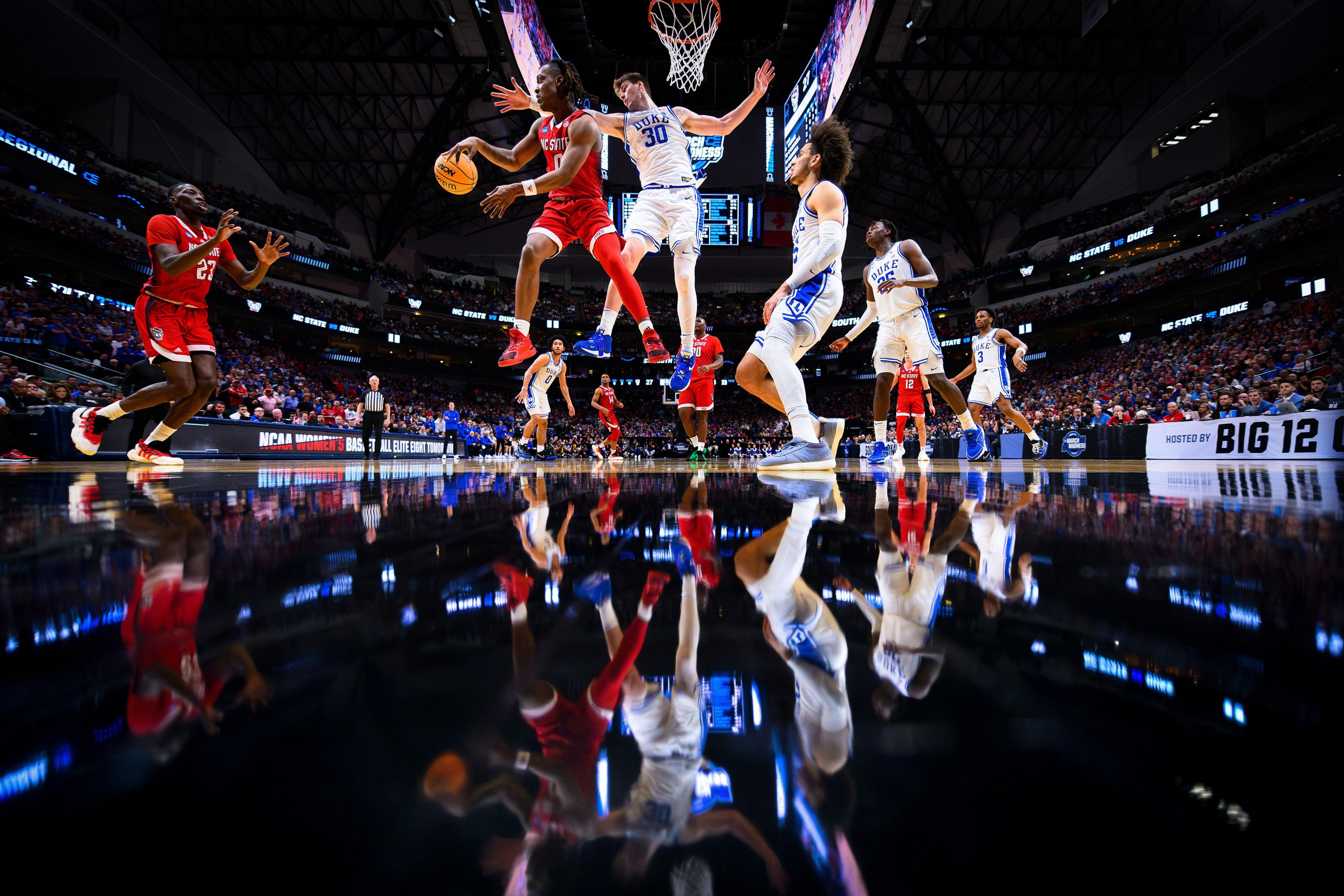 NC State guard DJ Horne dishes a pass to Mohamed Diarra while being defended by Duke's Kyle Filipowski during the Wolfpack's win over the Blue Devils in the Elite Eight matchup at American Airlines Arena in Dallas, Texas to advance to the Final Four of the NCAA men's basketball tournament