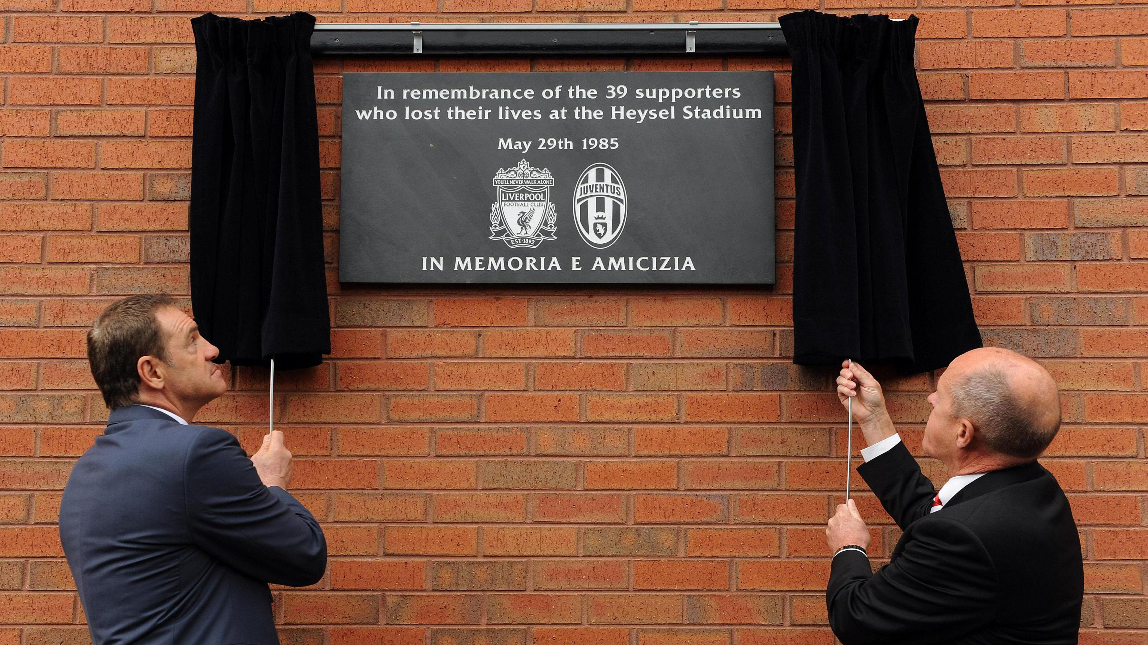 Two men unveil a memorial plaque at Anfield