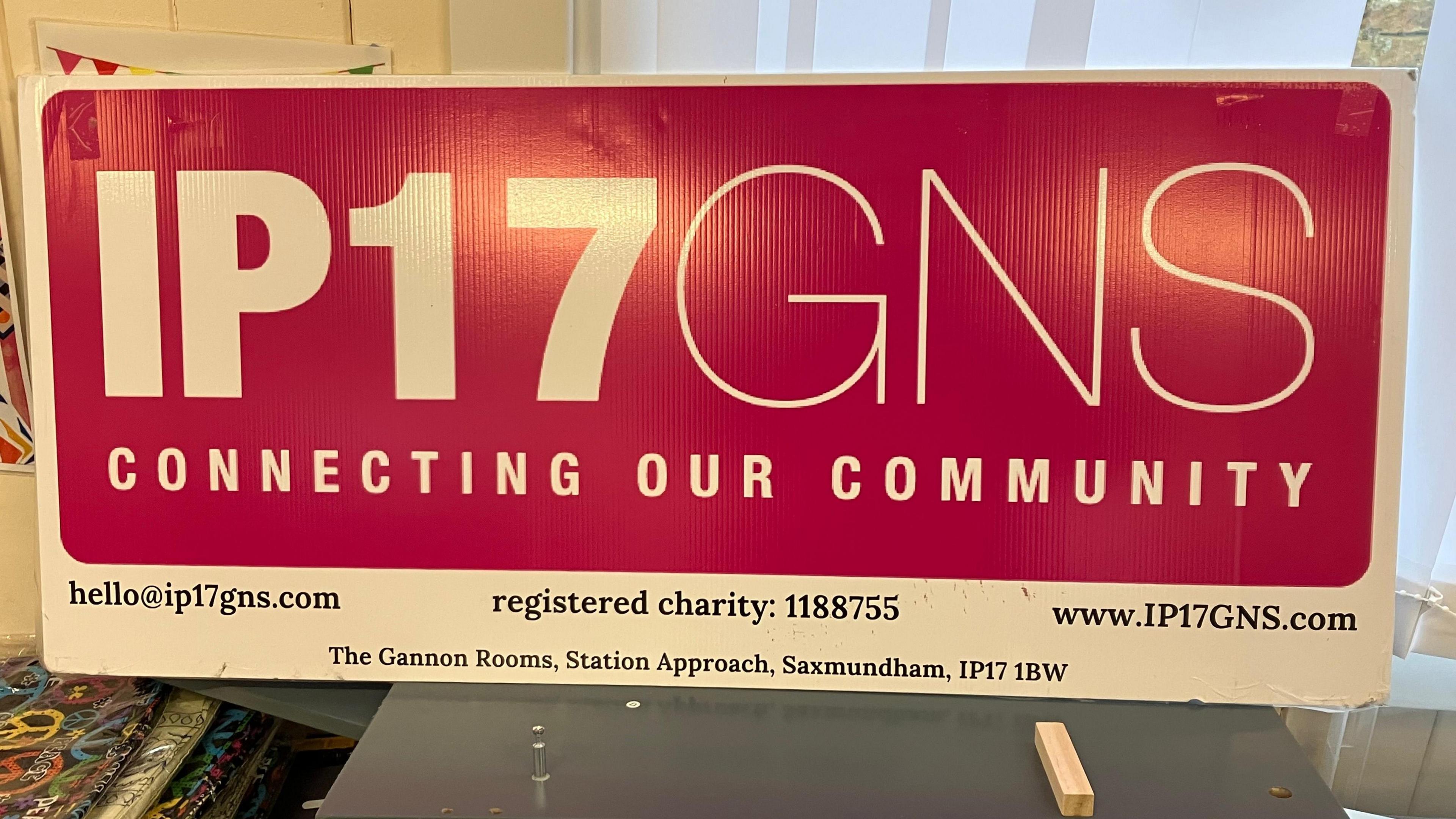 A red sign reading "IP17 GNS Connecting Our Community" is leaning against a window