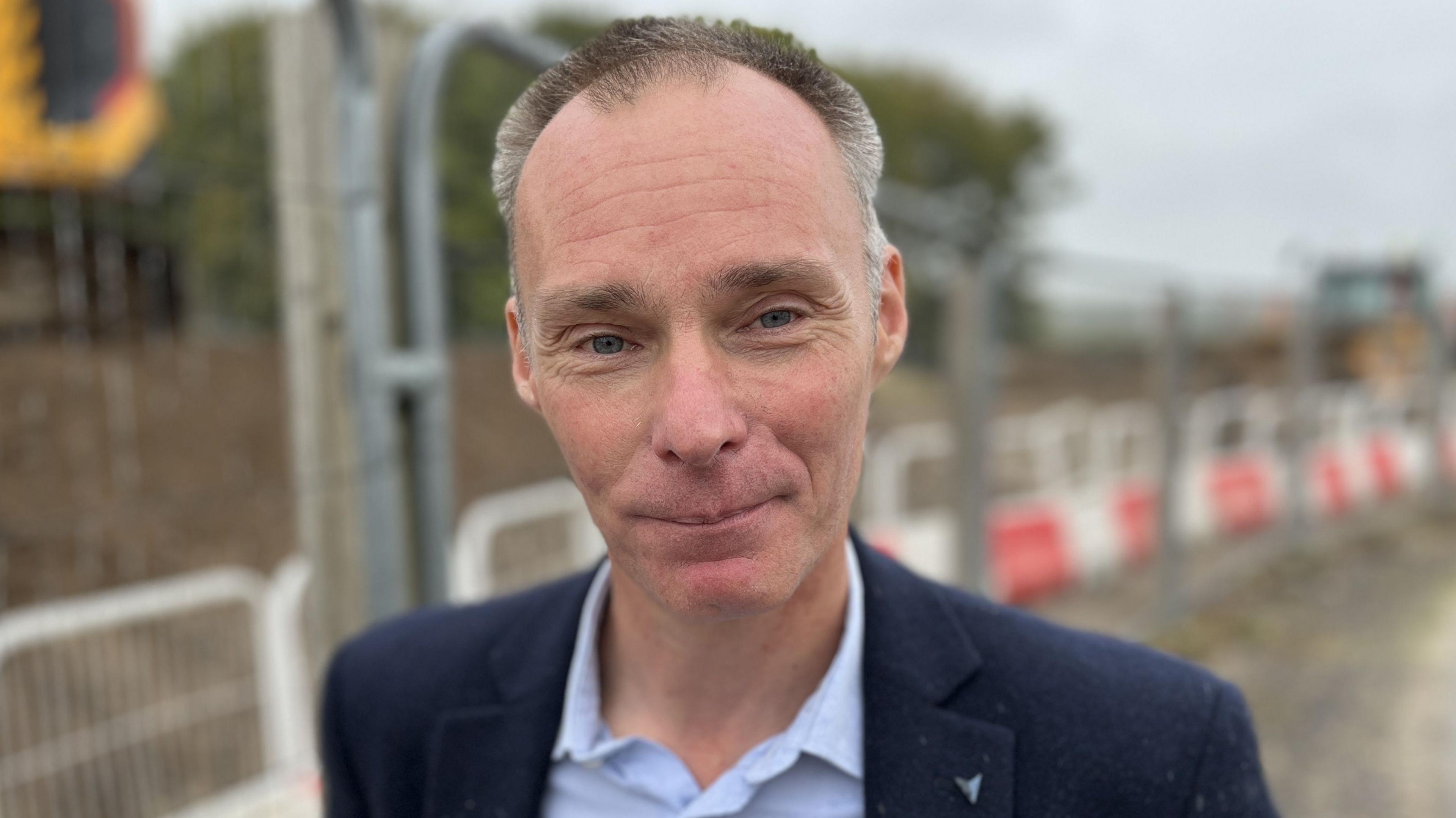 Laurence Stone with short grey hair wearing a navy blue blazer and light blue shirt