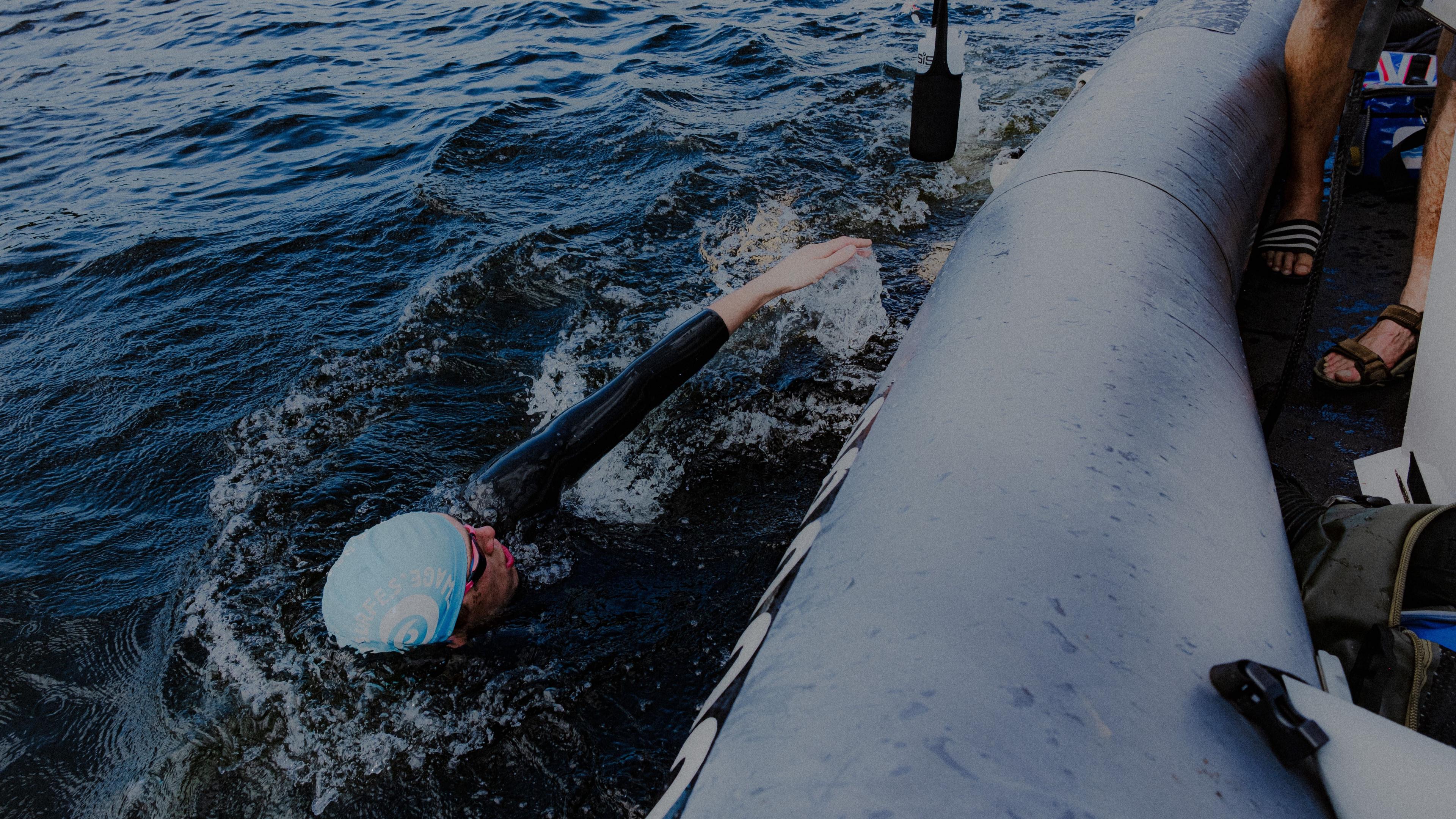 Haector Pardoe swimming alongside boat in lake