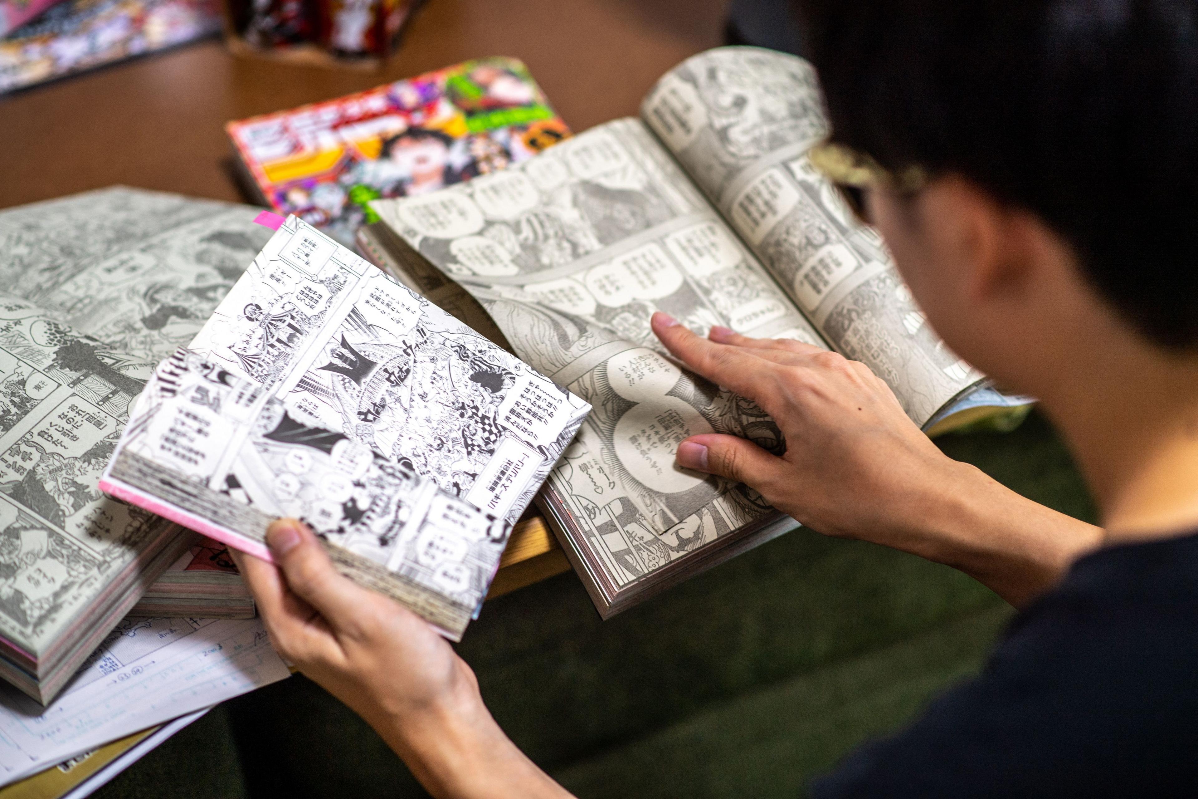 A young Japanese boy reading multiple copies of the One Piece manga