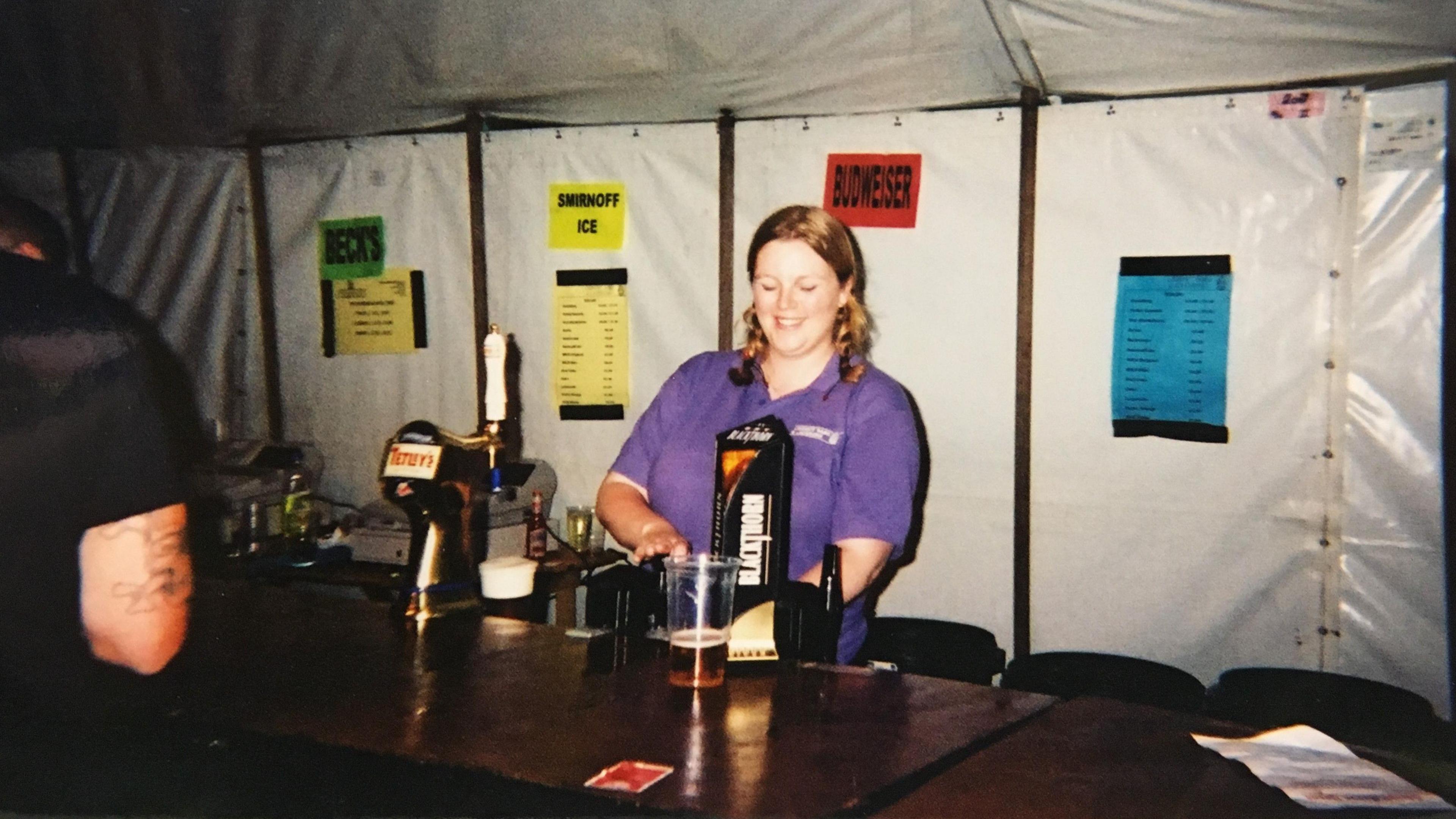 Penny Hansen in a purple shirt pulling a pint at the bar