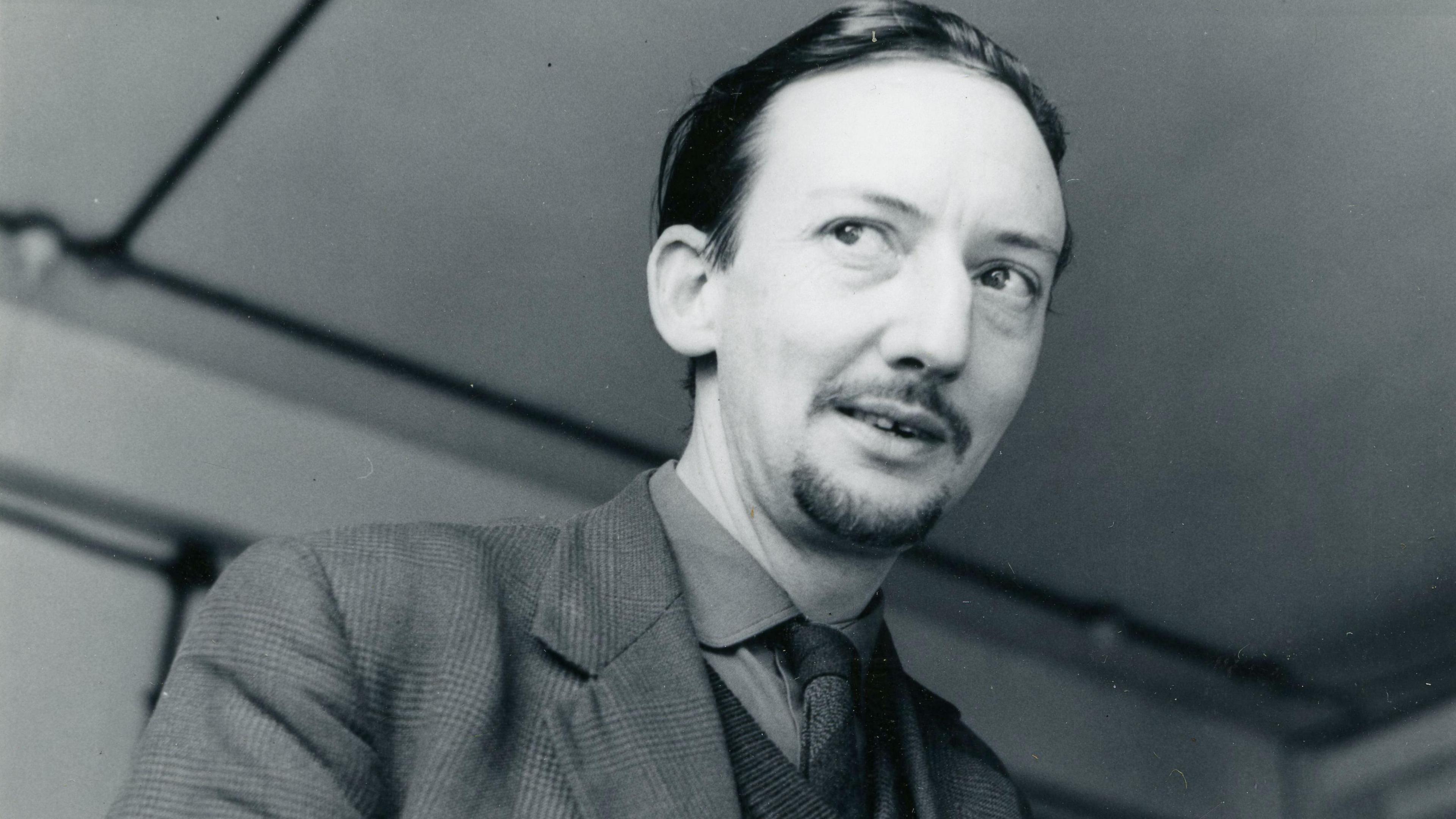 A black and white image of Eric Gorton, wearing a suit jacket and tie