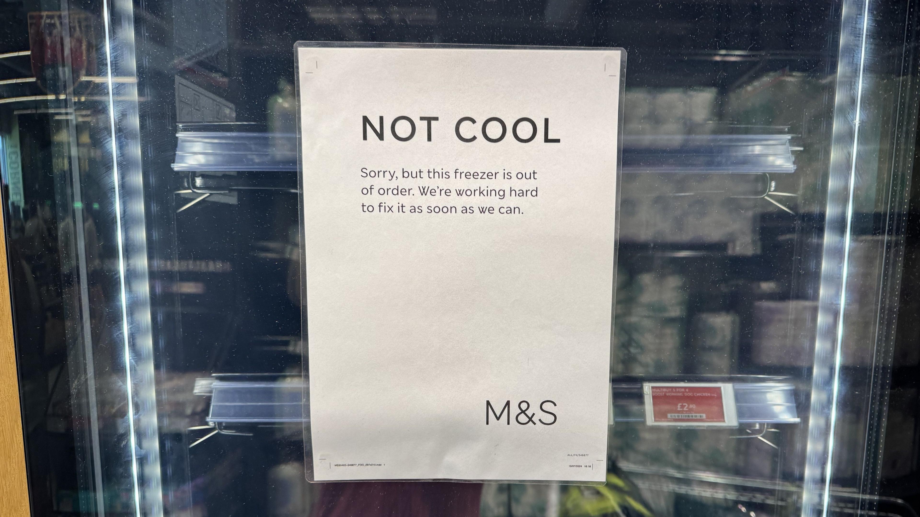 Supermarket freezer door, with sign saying: "NOT COOL Sorry, but this freezer is out of order. We're working hard to fix it as soon as we can."