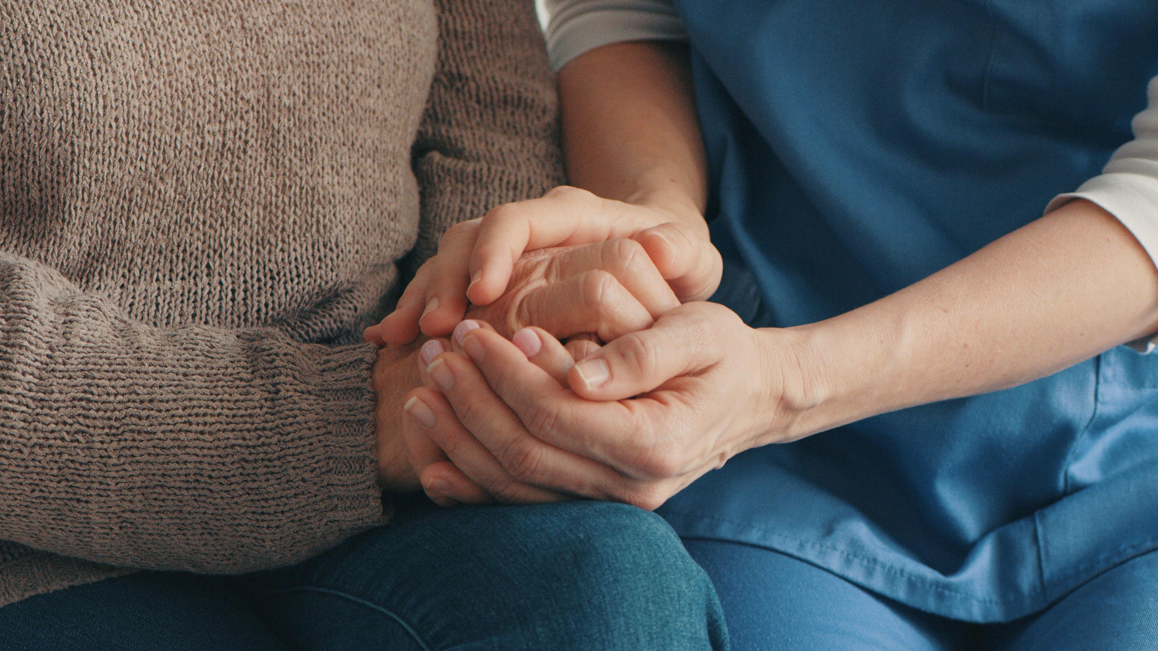 Two people holding hands. One is wearing blue scrubs.