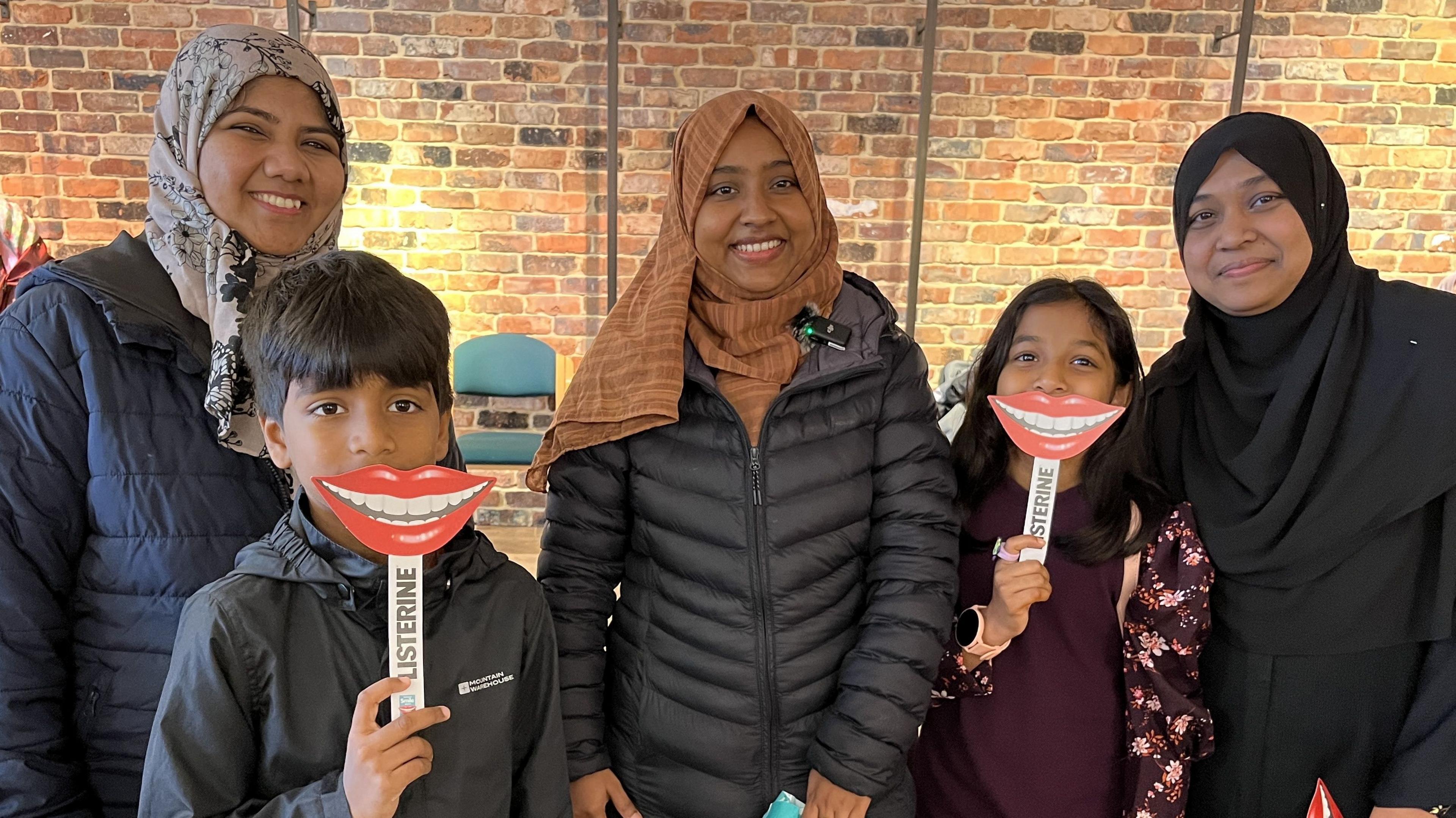 Migrants from Sri Lanka, Africa and India wearing hijabs and smiling with their children