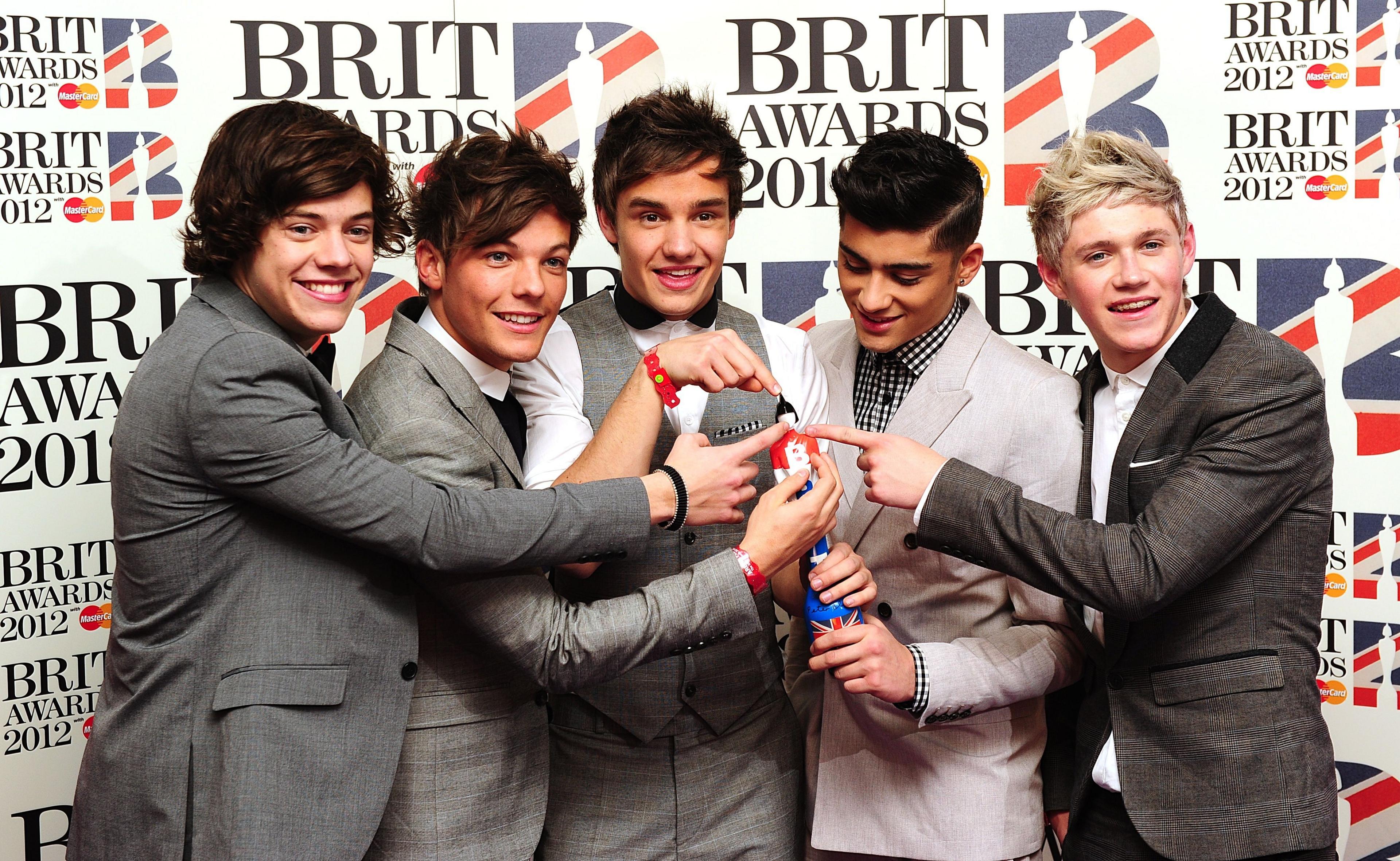 Five young men pose with an award on a red carpet 