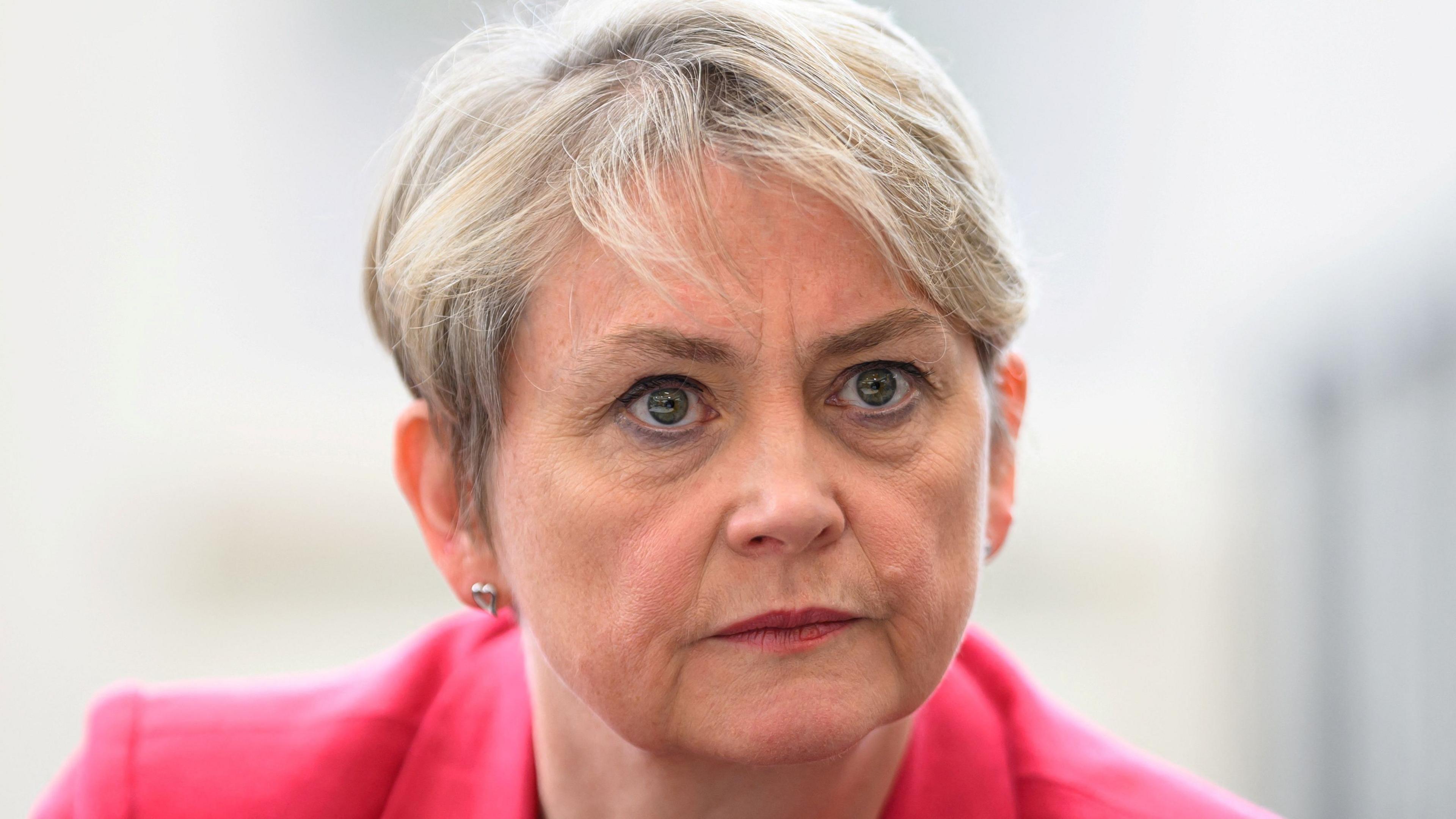 Yvette Cooper, who has cropped blonde hair, looks on during a visit to a library