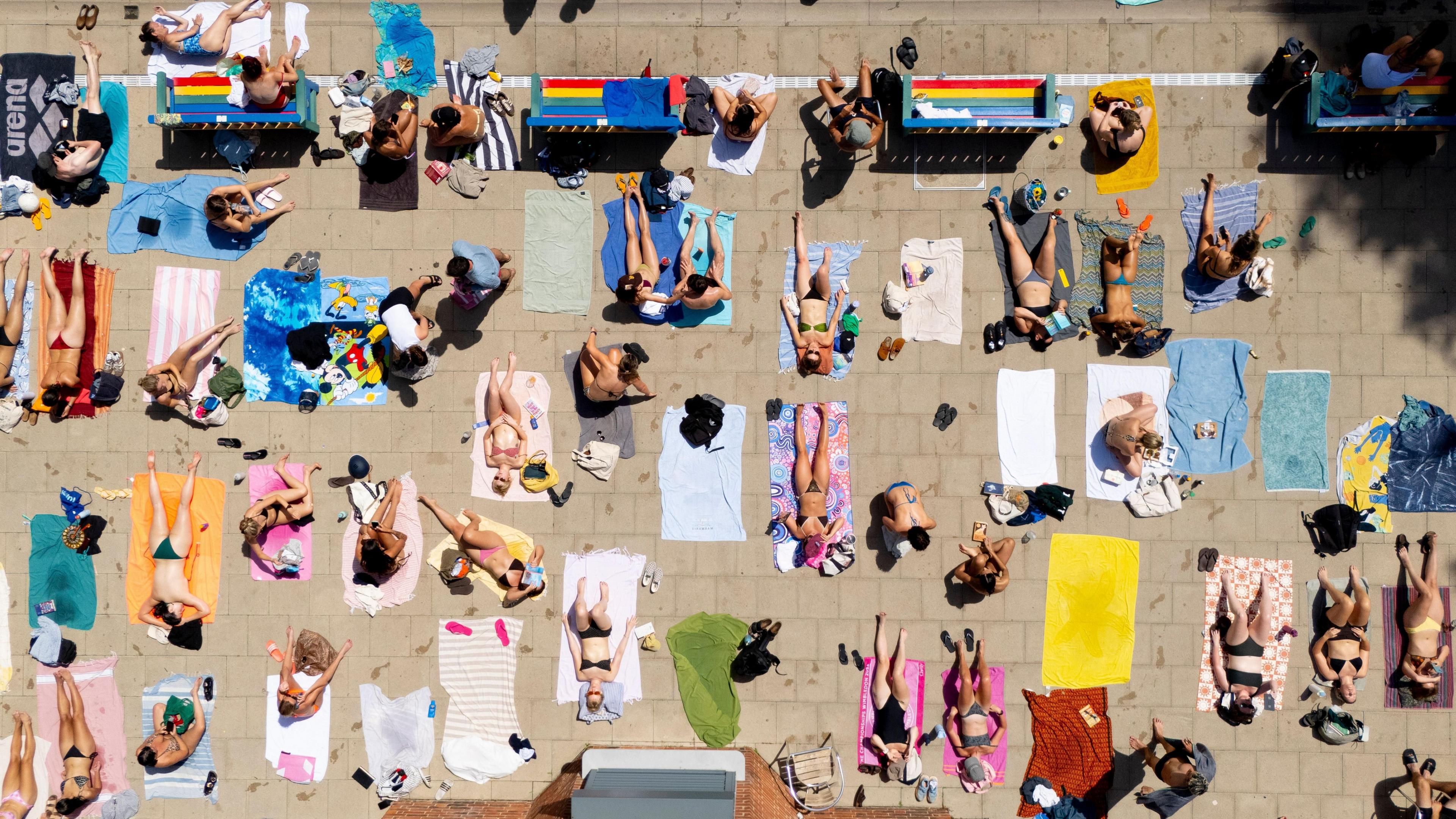 An aerial view taken with a drone shows people sunbathing and swimming at London Fields Lido.
