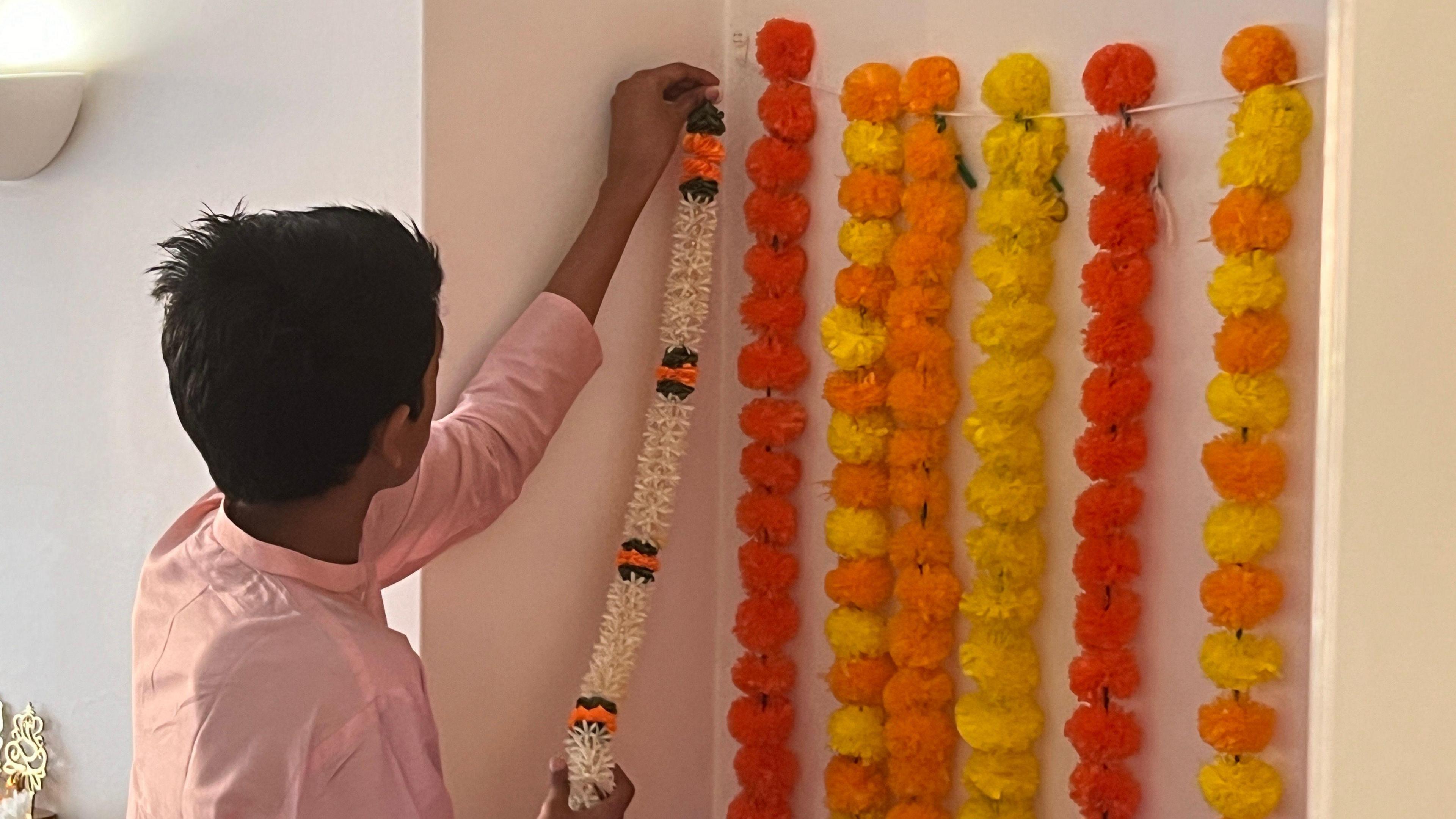 A man hanging up Indian pom pom garlands