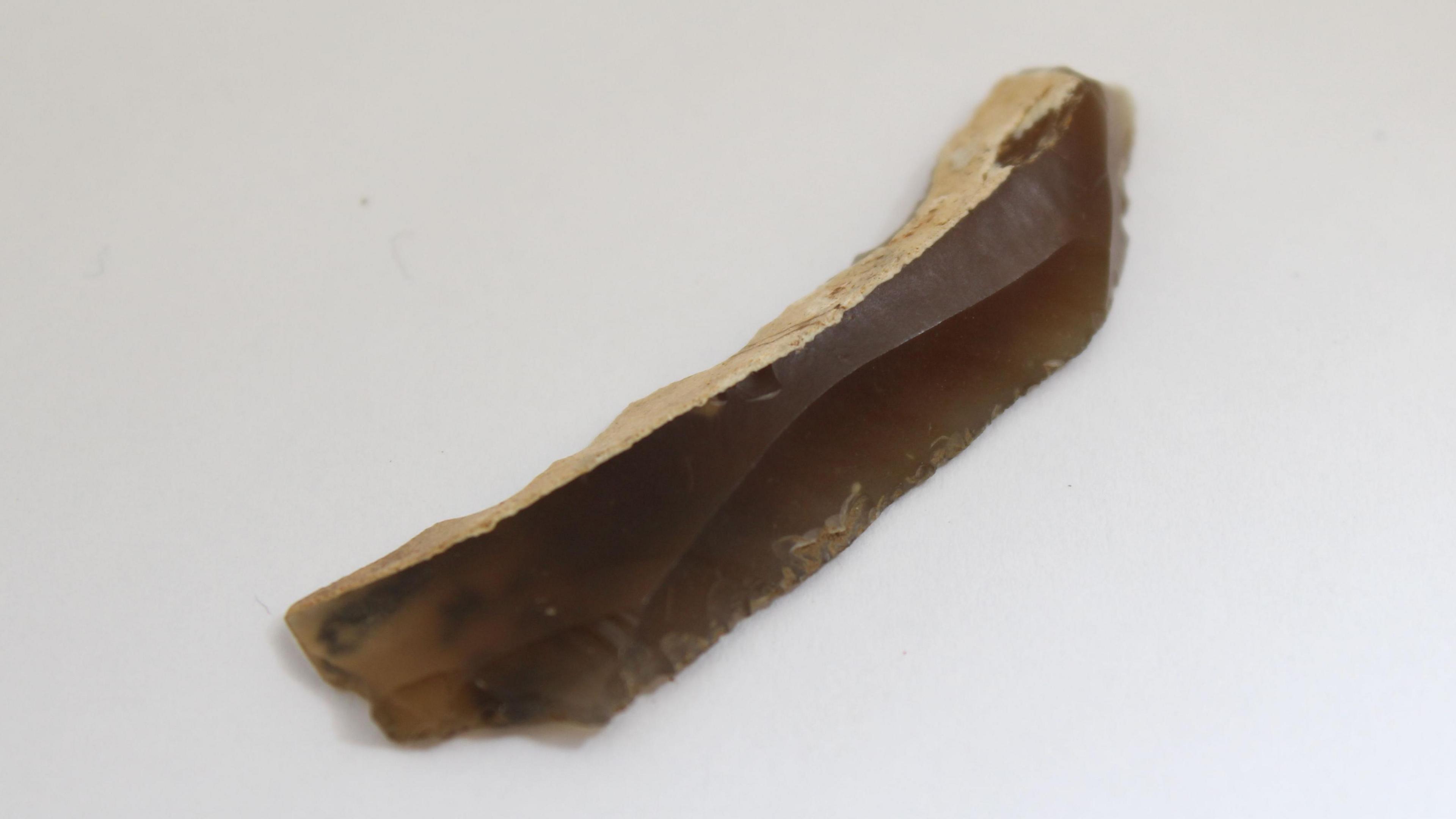 A Mesolithic flint blade placed on a plain white background