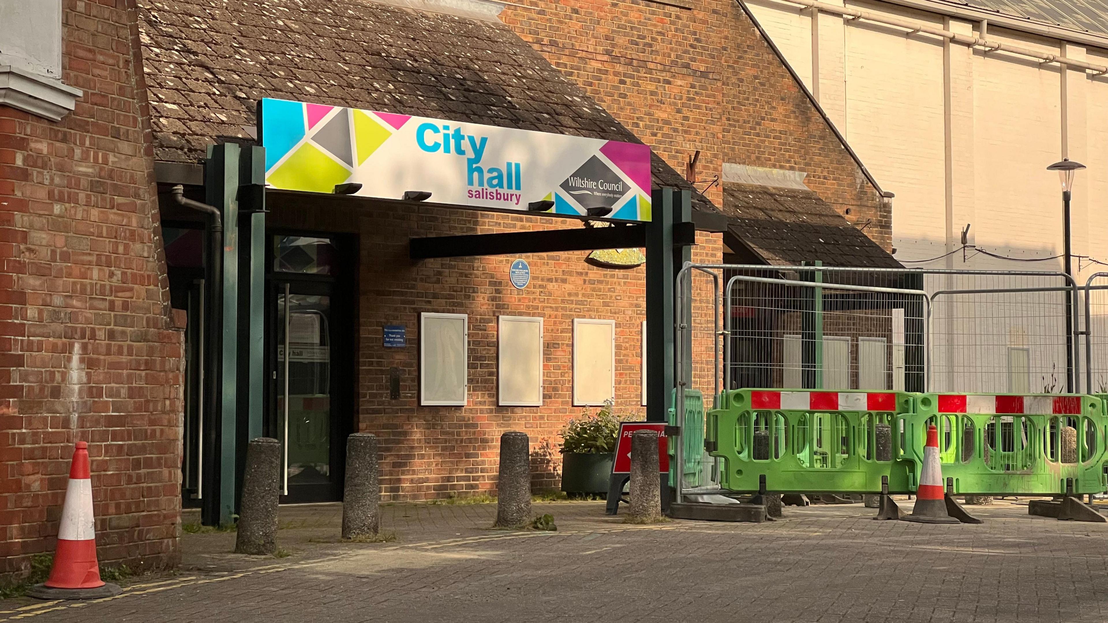 A photo showing the entrance to Salisbury's City hall with cones and a green barrier either side