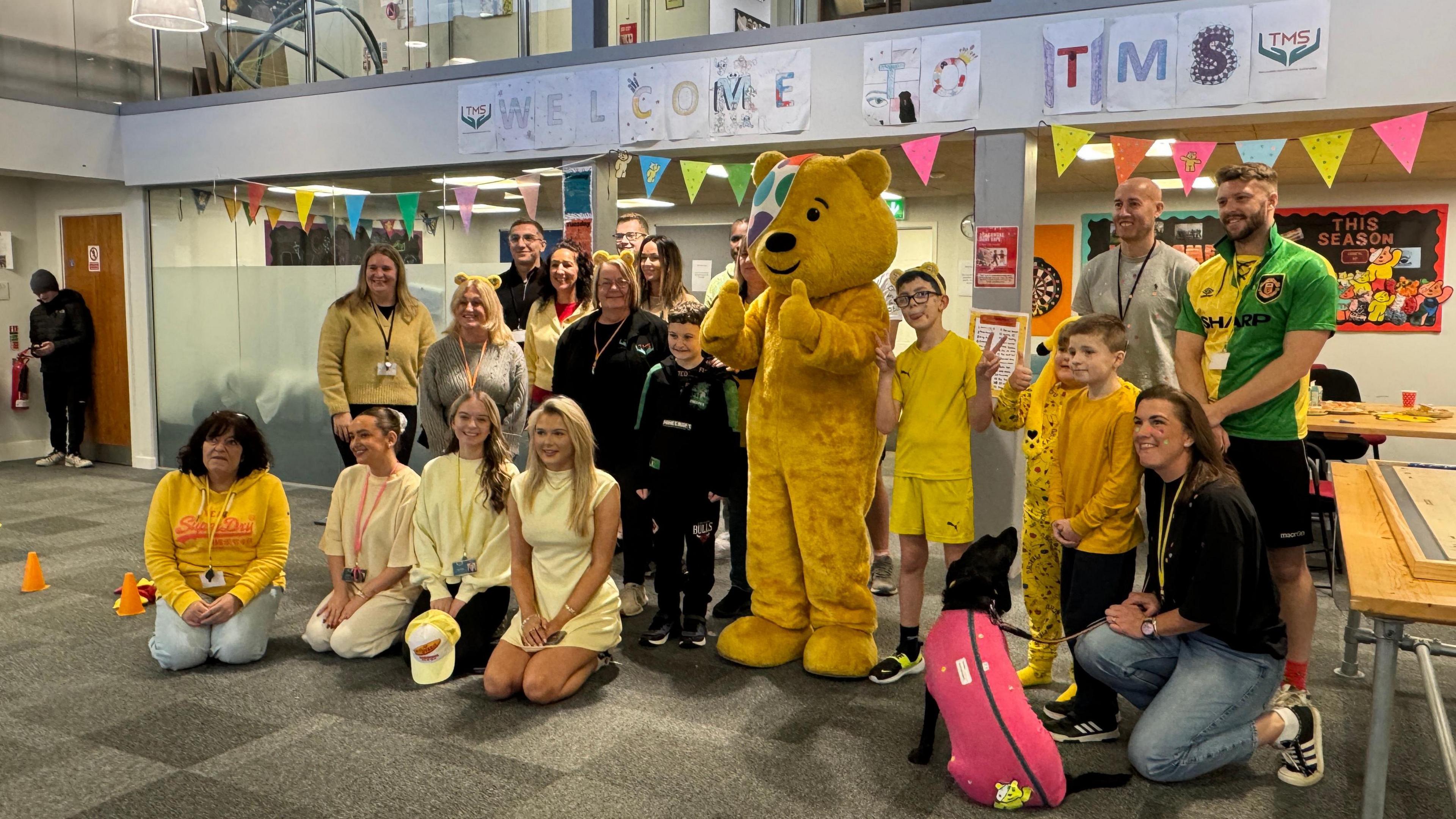 Pudsey bear with a group of adults and children at Taylored Mentoring in Gloucestershire.