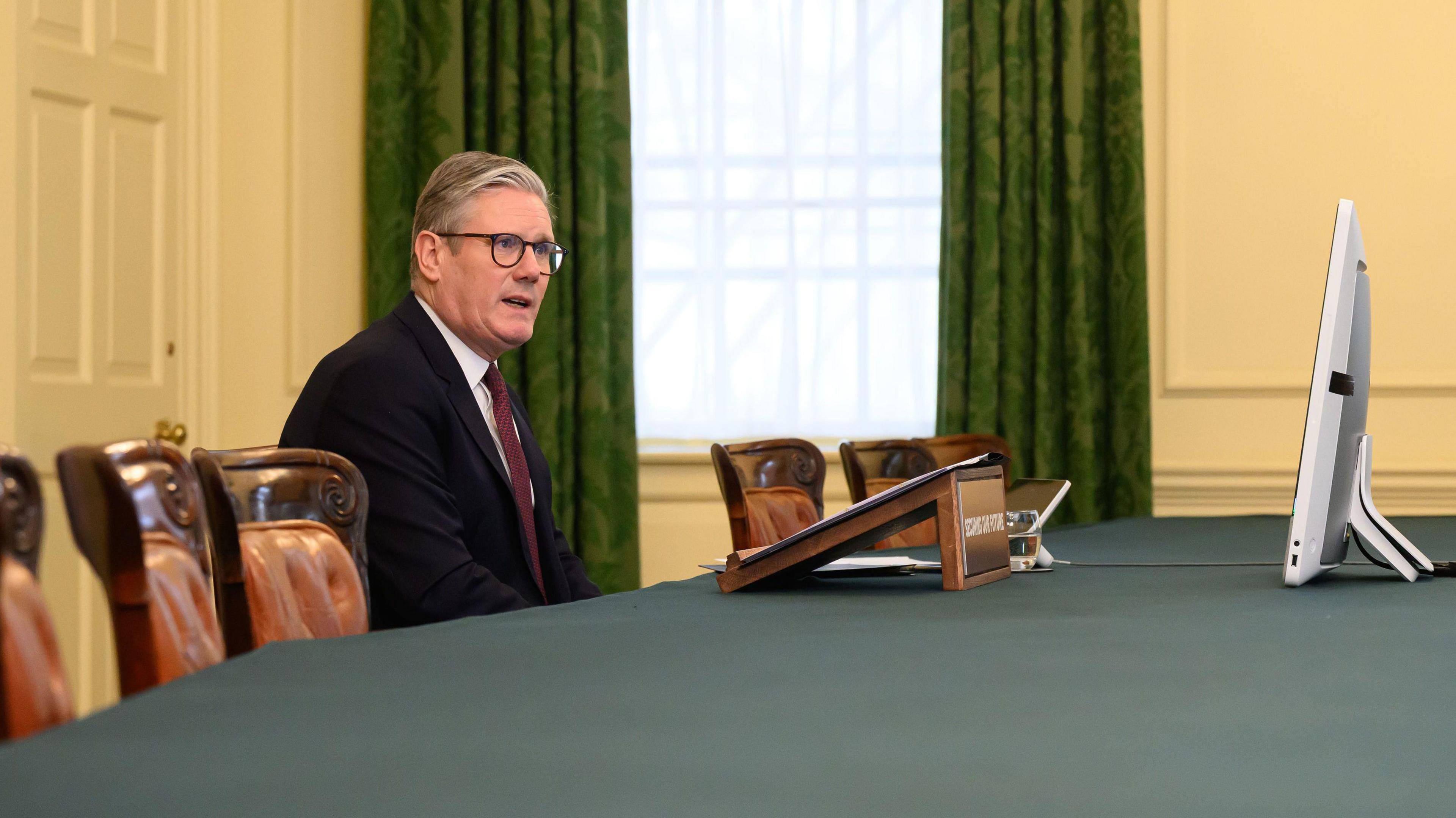 Sir Keir Starmer sits in an otherwise empty cabinet meeting room talking to a computer screen.