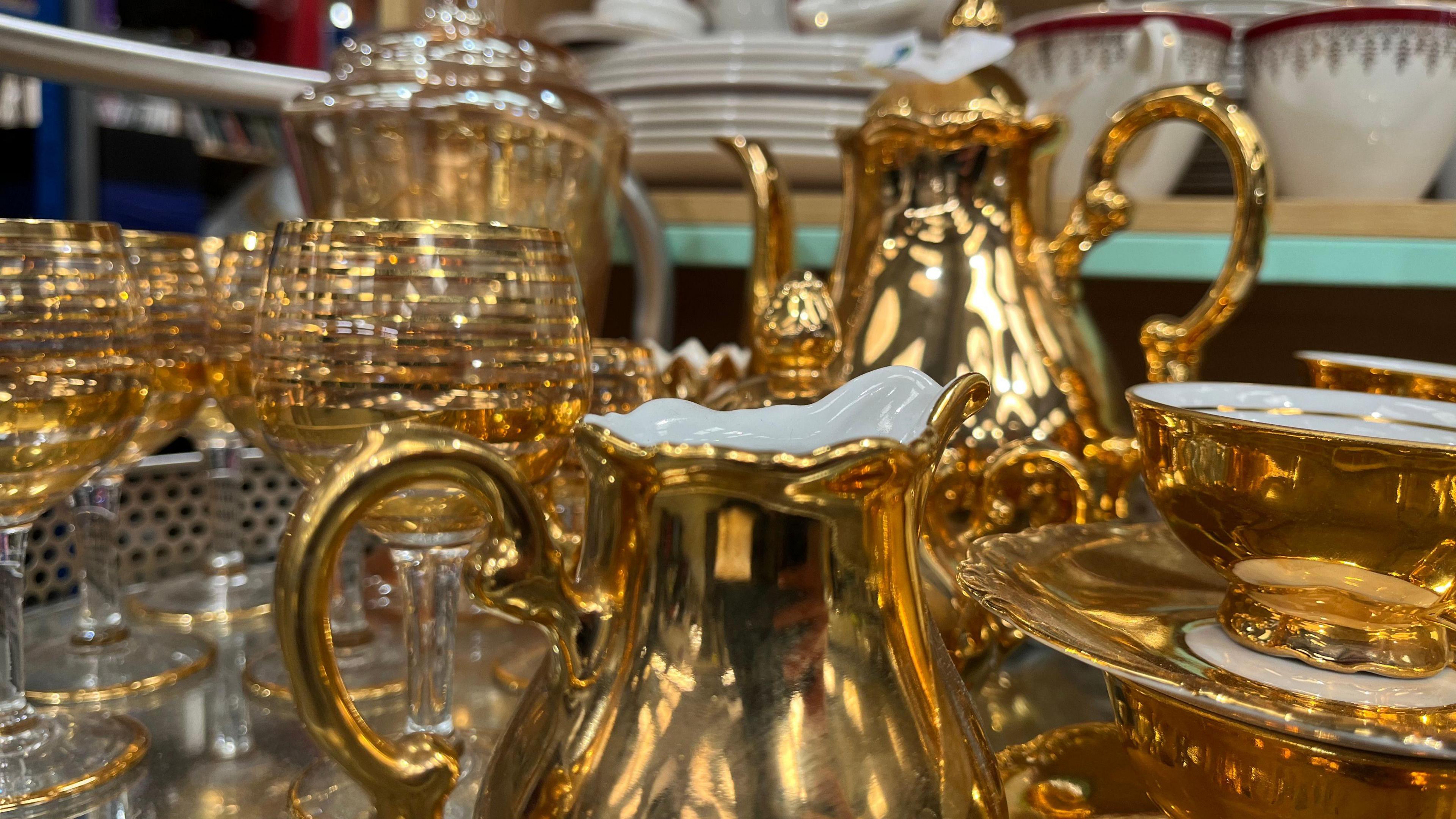 A shiny gold tea-set close, reflections bouncing off