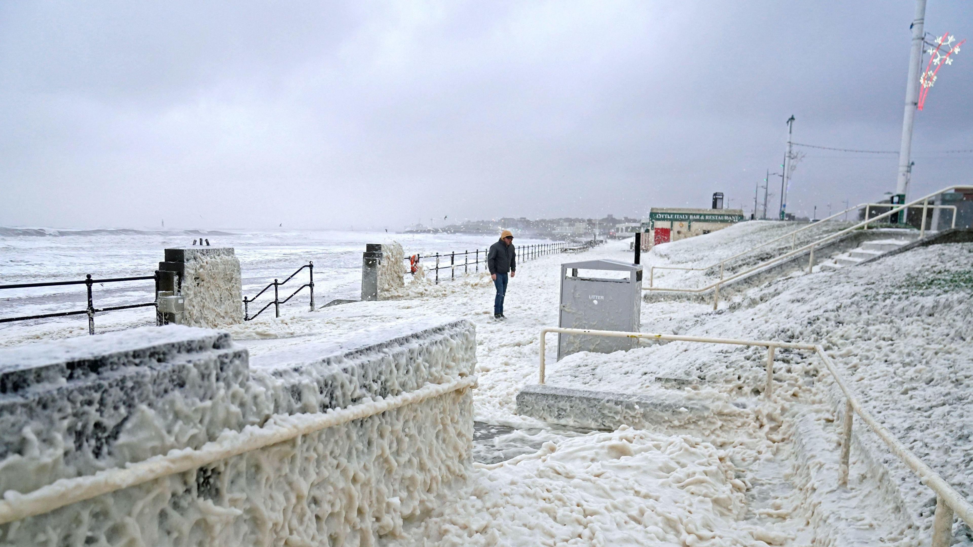 A man walks through sea foam in Seaburn, Sunderland, as Storm Babet batters the country.