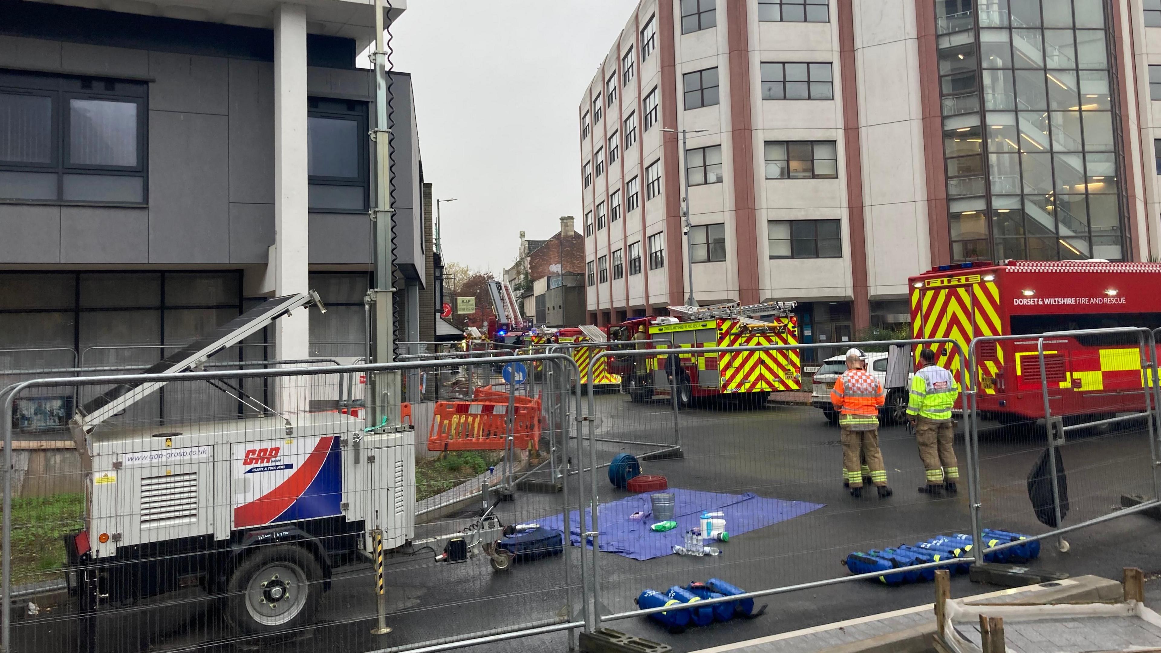 A photograph from behind a fire cordon showing four fire engines parked along the street where the fire took place