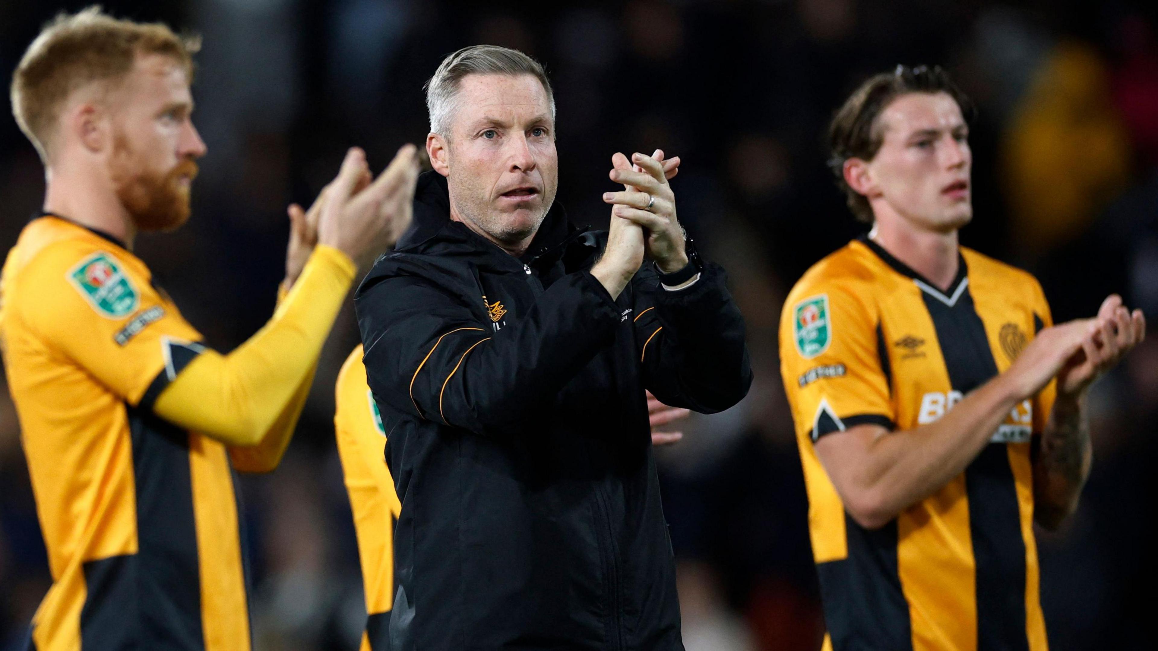 Cambridge boss Neil Harris and his players applaud their travelling supporters following the game at Craven Cottage