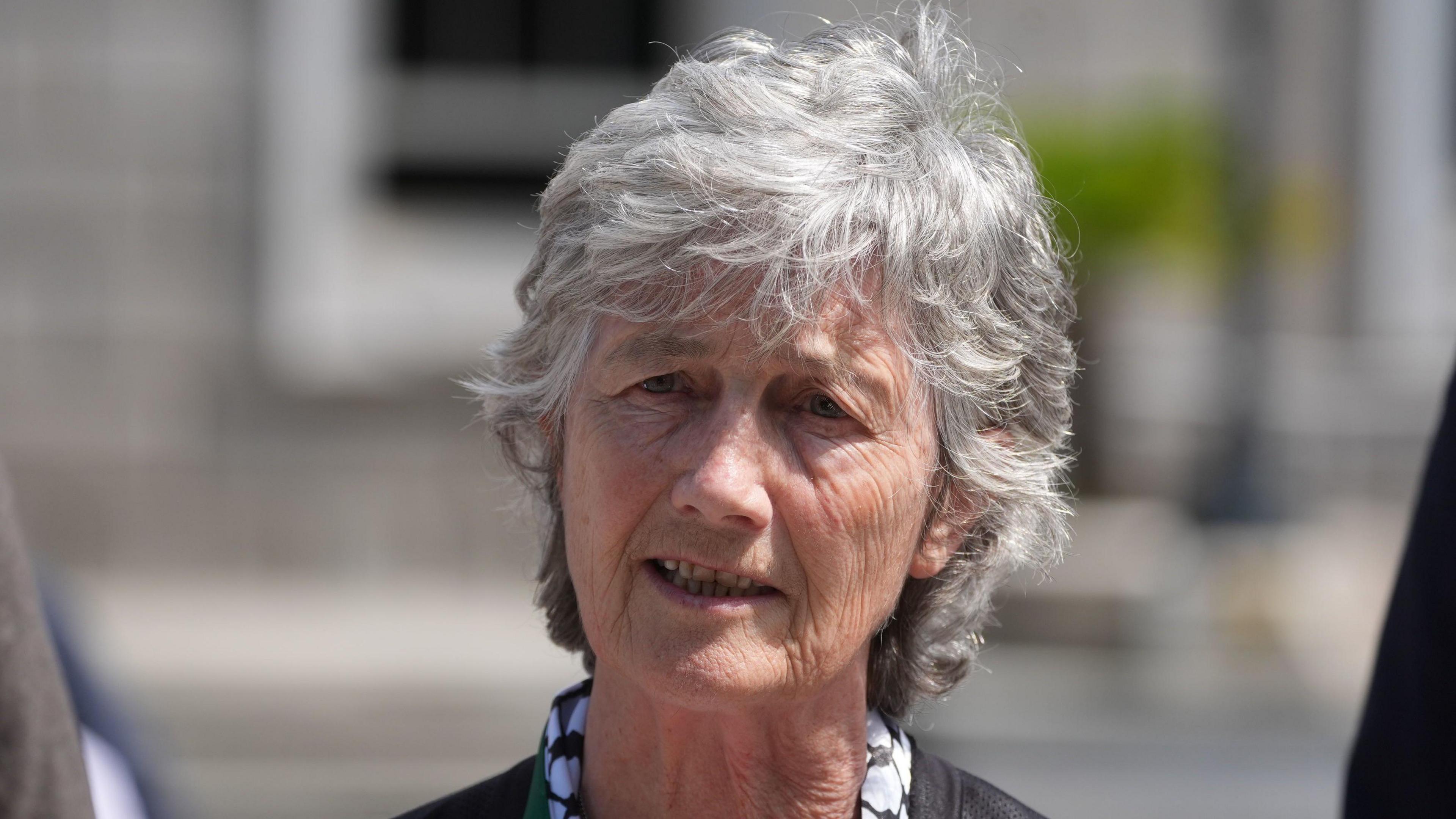 Catherine Connolly has short grey hair and is speaking as the picture is taken. The background behind her is blurred.