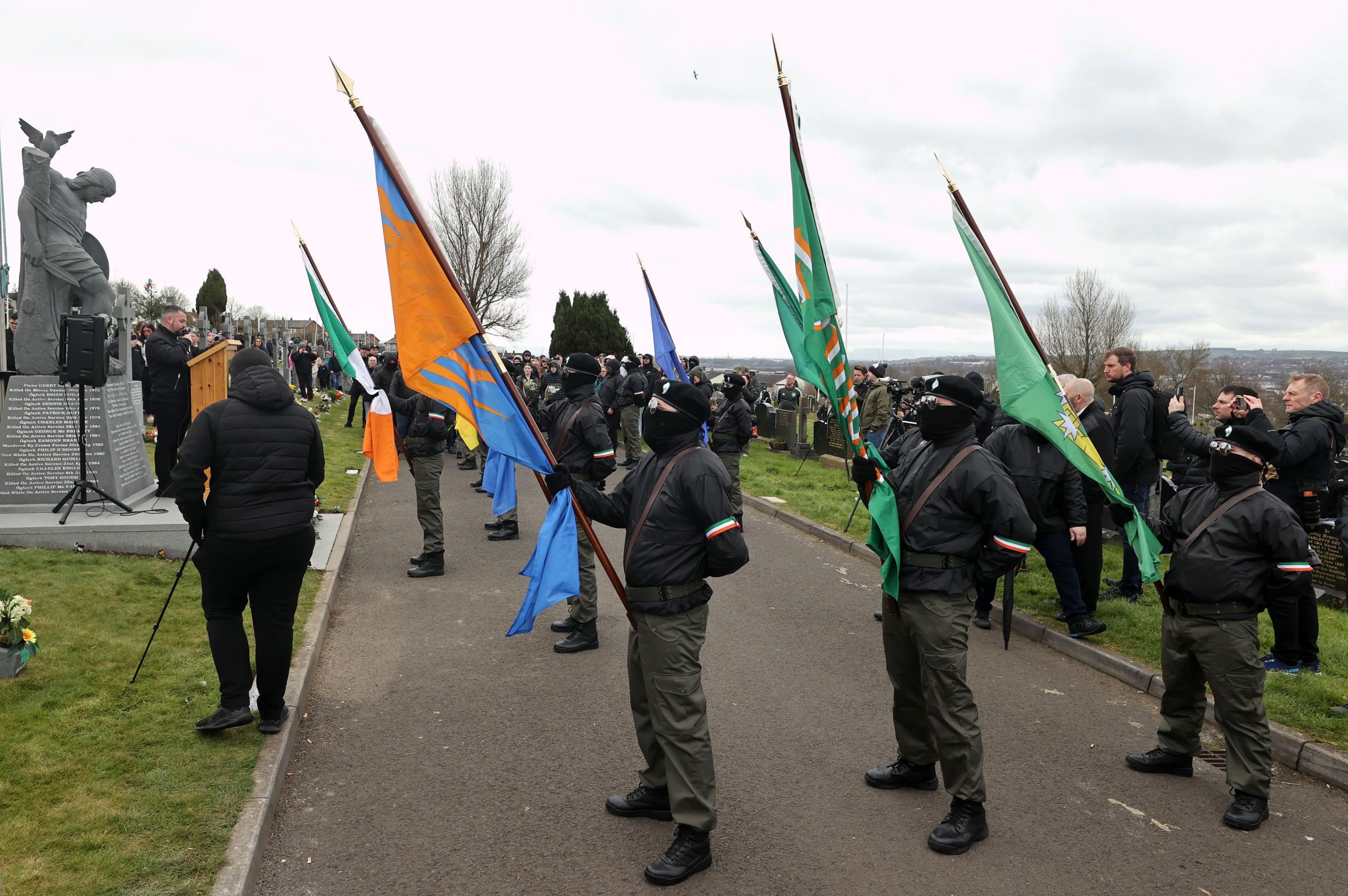 Masked men in paramilitary-style uniforms lead the march through Creggan to the city cemetery