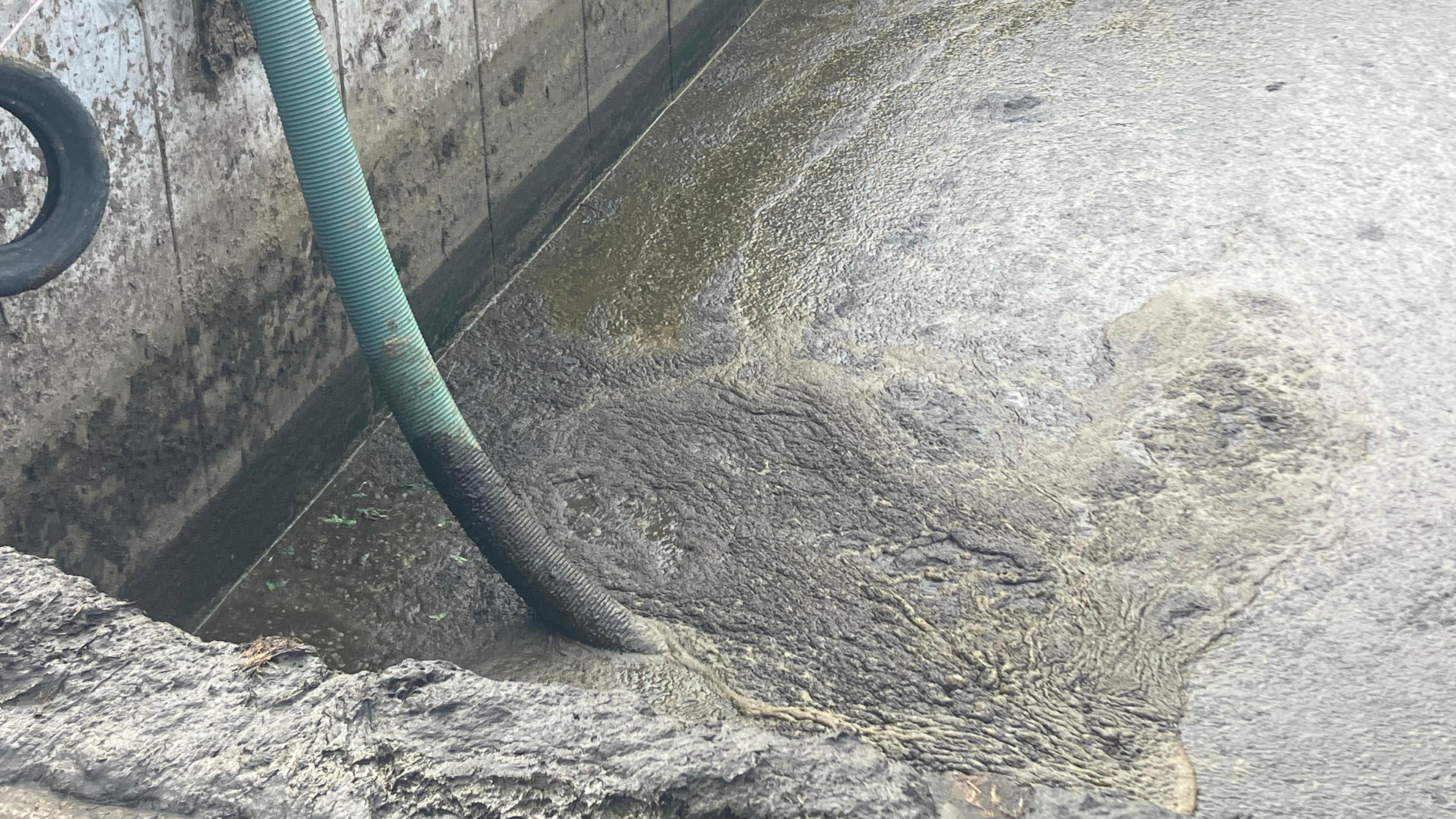 A pipe is lowered into a slurry pit.  