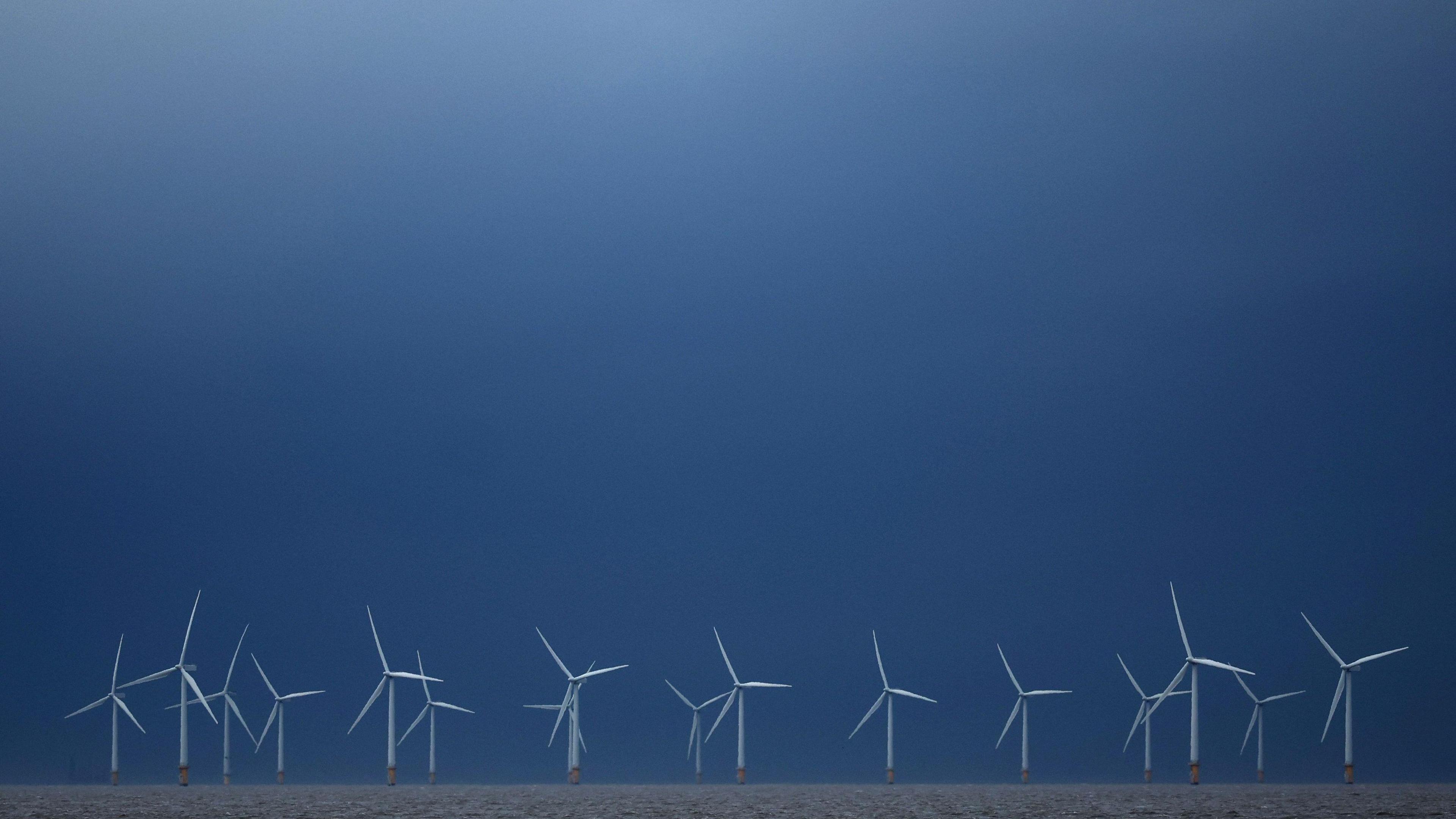 Rhes o 16 o dyrbinau gwynt ar waelod y llun, gyda'r awyr uwchben yn las tywyll